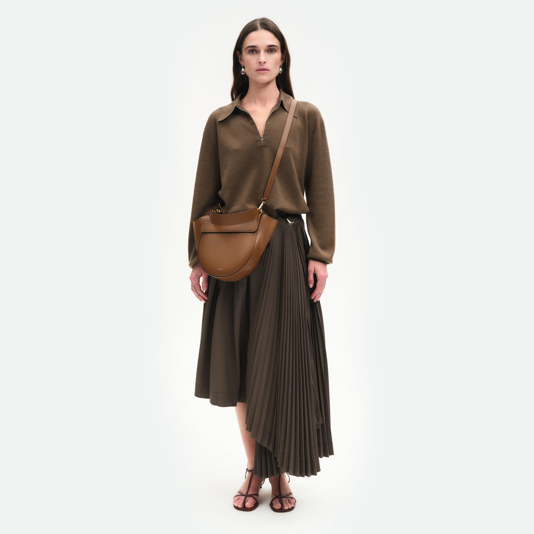 Wandler Hortensia Bag Medium in the color Saddle, warm brown, made from Italian calf leather with golden hardware, rounded silhouette and top handle, pictured on model being worn in crossbody style. 
