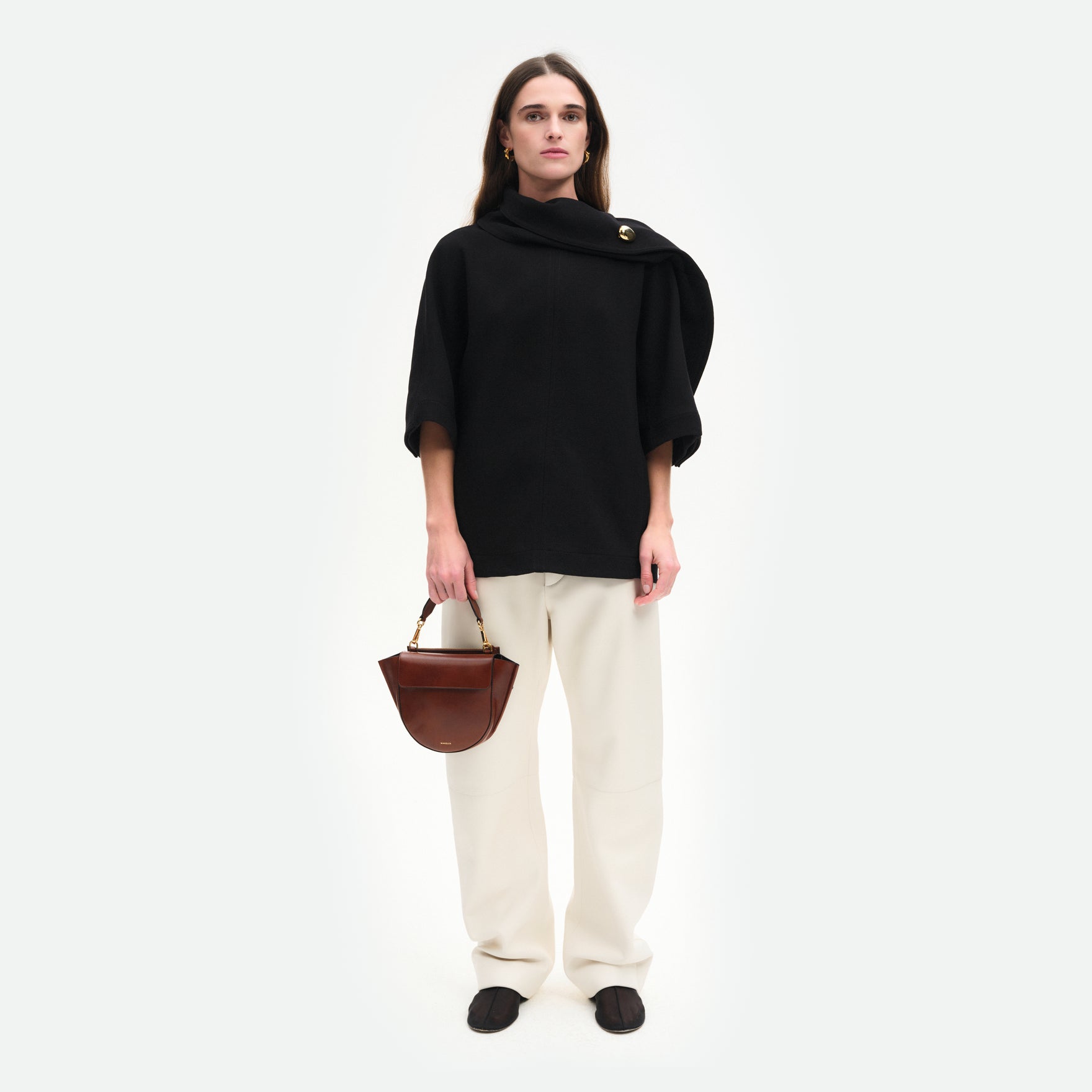 Wandler Hortensia Bag Mini in the color Palissander Glaze, deep dark brown with red undertones, made from Italian calf leather with golden hardware, rounded silhouette and top handle, pictured on model being handheld, full body picture.