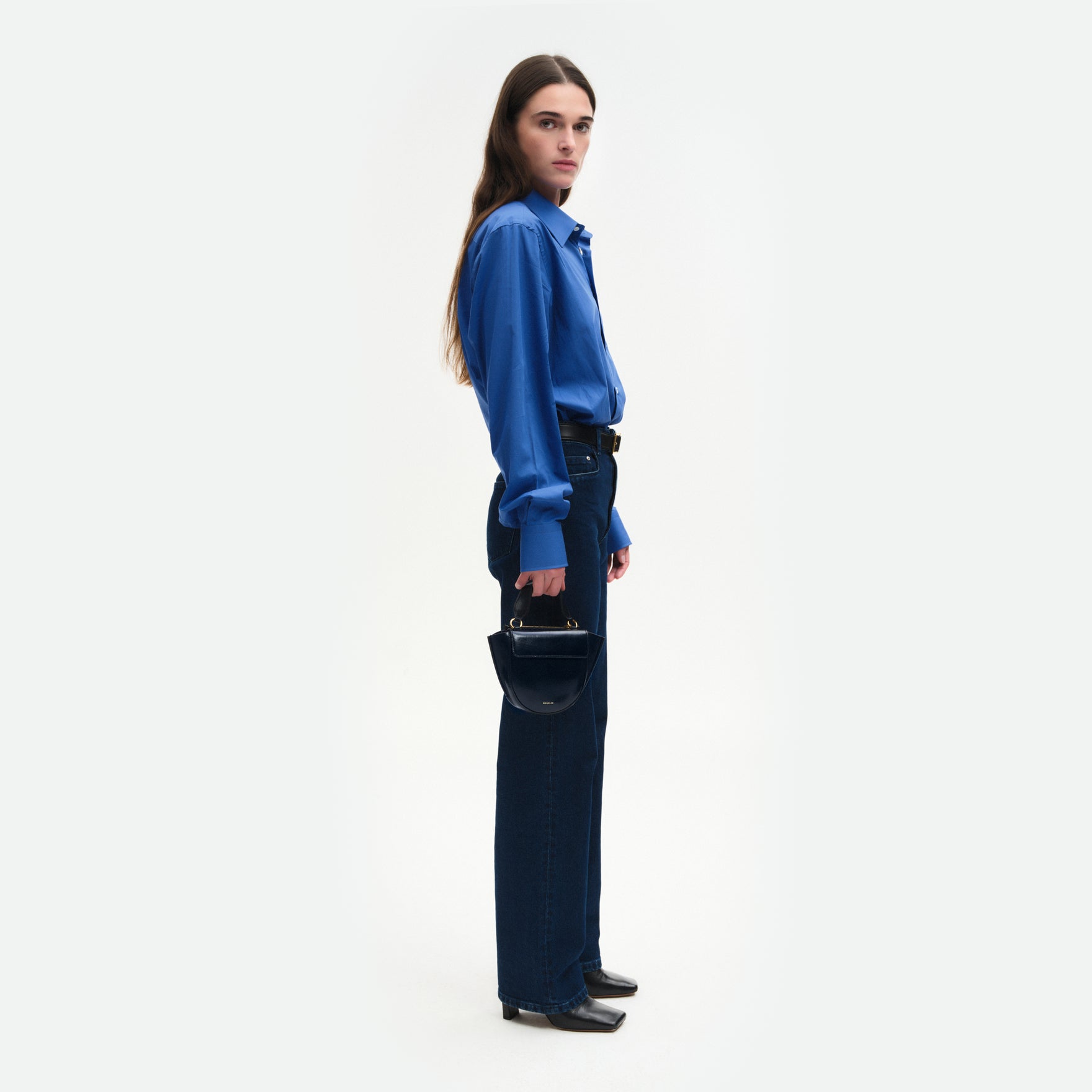 Wandler Hortensia Bag Piccola in the color Orion Glaze, shiny dark blue, made from Italian calf leather with golden hardware and rounded silhouette, pictured being handheld by model, full body picture.