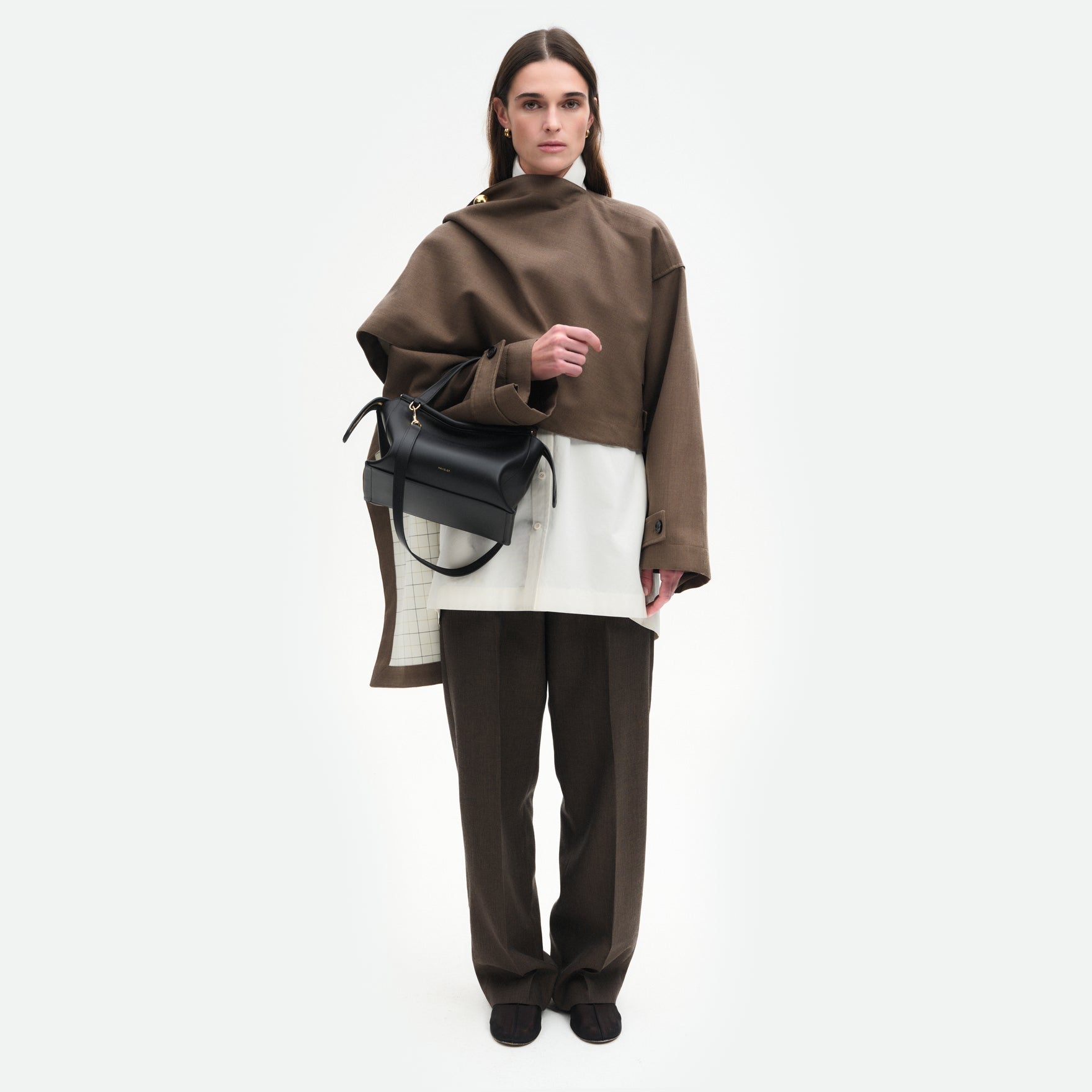 Wandler Ida Bag in the color Black, made from Italian calf leather with golden hardware and sculptural top handle, pictured being worn on the forearm by model.