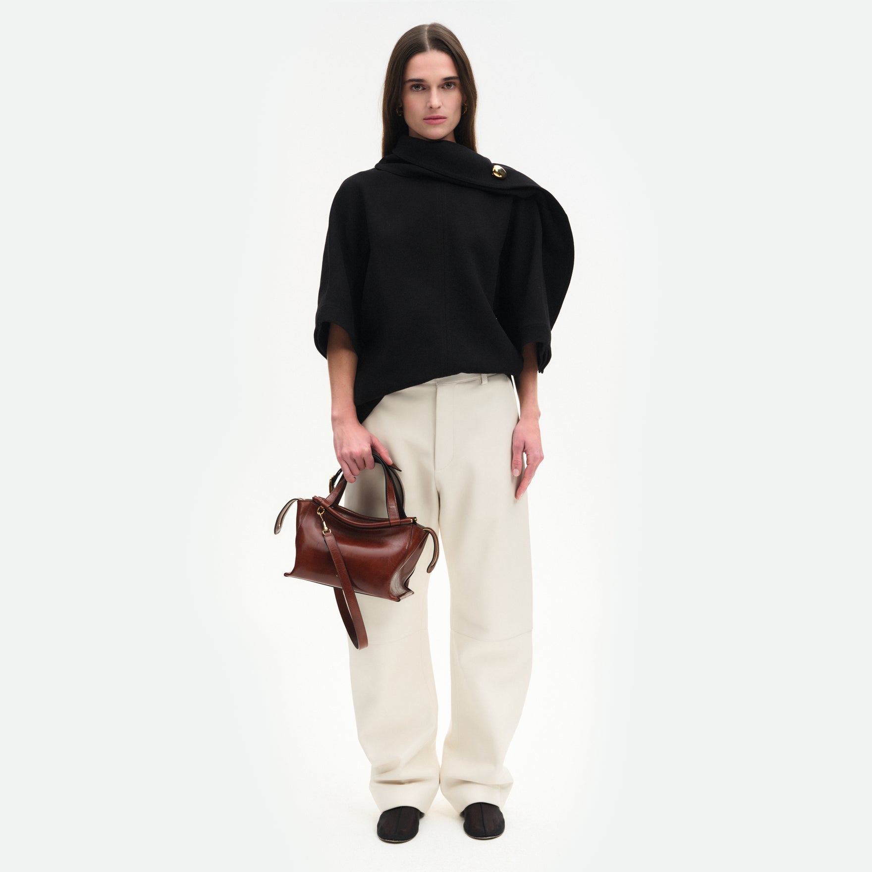 Wandler Ida Bag in the color Palissander Glaze, deep dark brown with red undertones, made from Italian calf leather with golden hardware and sculptural top handle, pictured being hand held by model.