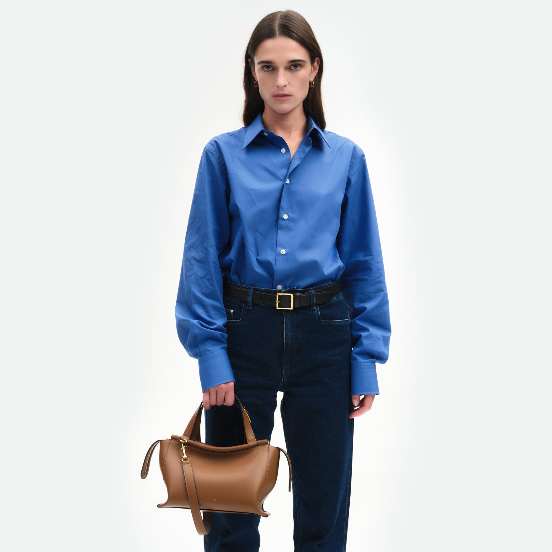 Wandler Ida Bag in the color Saddle, warm brown, made from Italian calf leather with golden hardware and sculptural top handle, pictured being hand held by model, half body picture.