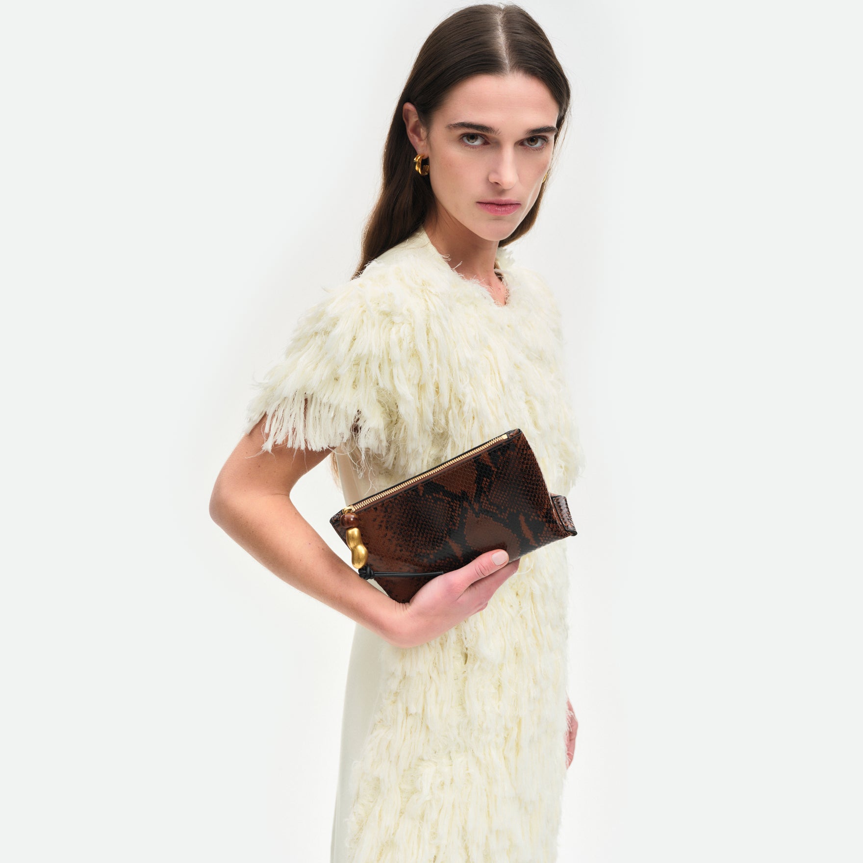 Wandler Ida Case in Brown Python soft calf leather with golden zipper hardware and charm, being held in the hand by model. 