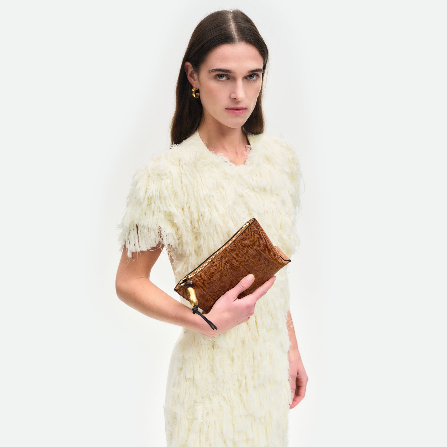 Wandler Ida Case in Tabacco Lizzard, soft calf leather with golden zipper hardware and charm, being held in the hand by model.