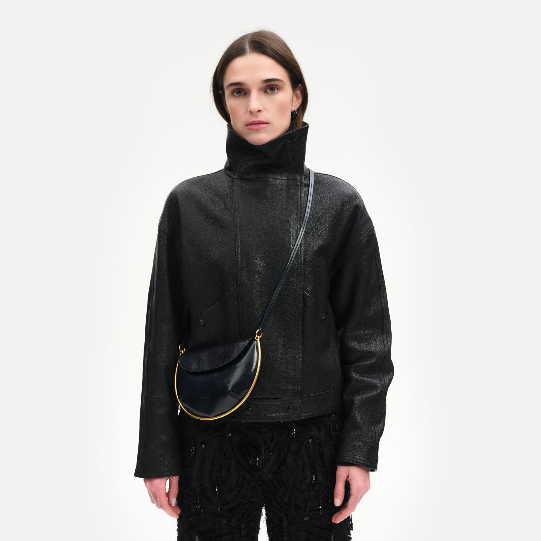 Wandler Kate Mini Crossbody in the color Orion Glaze, deep dark blue, made from Italian calf leather with golden hardware and adjustable strap, pictured on model, worn in crossbody style, half body picture. 