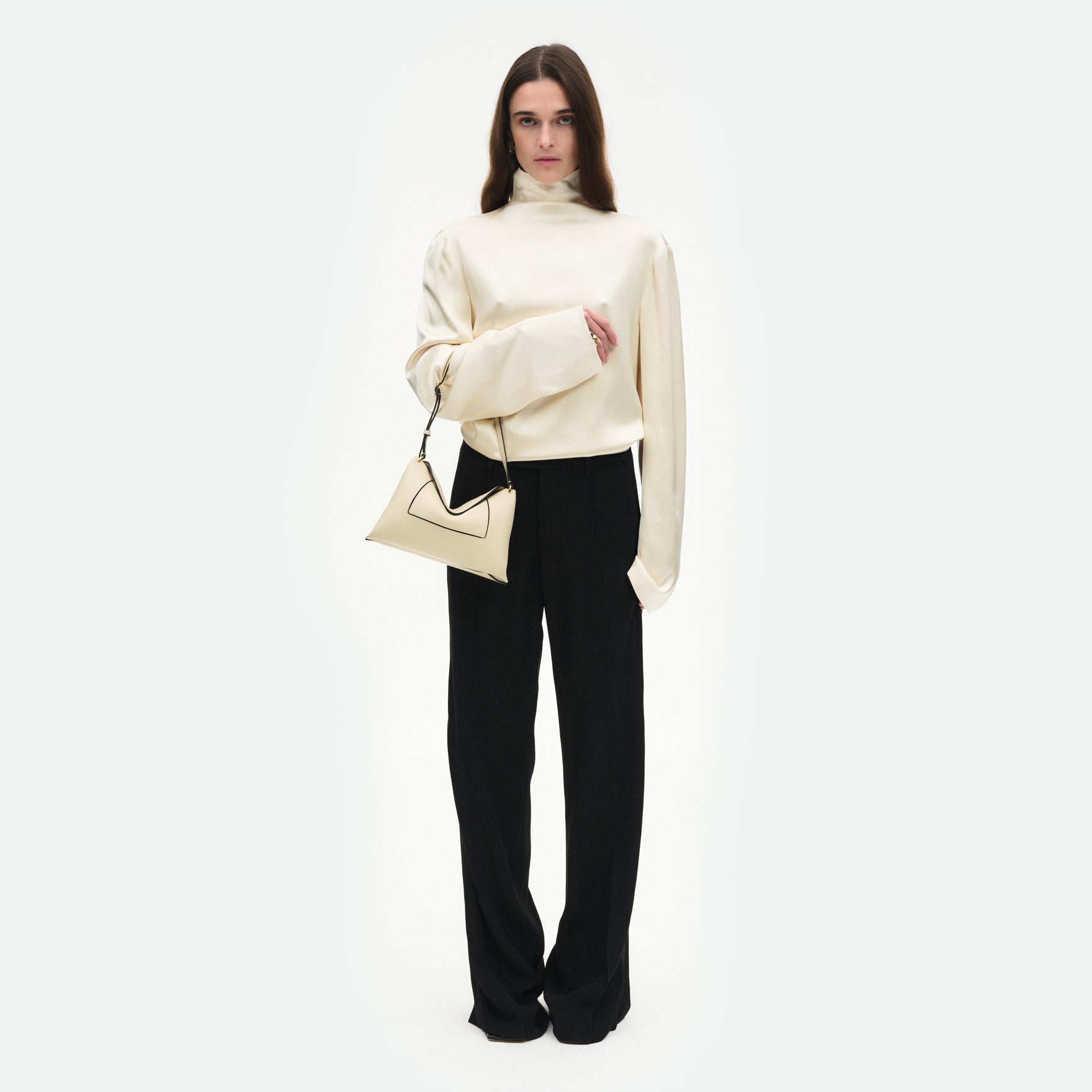 Wandler Penelope Slouch Bag in the colour Beige Crust, beige, made from smooth calf leather with golden hardware and adjustable slim strap, pictured on model, worn on the forearm, front view.