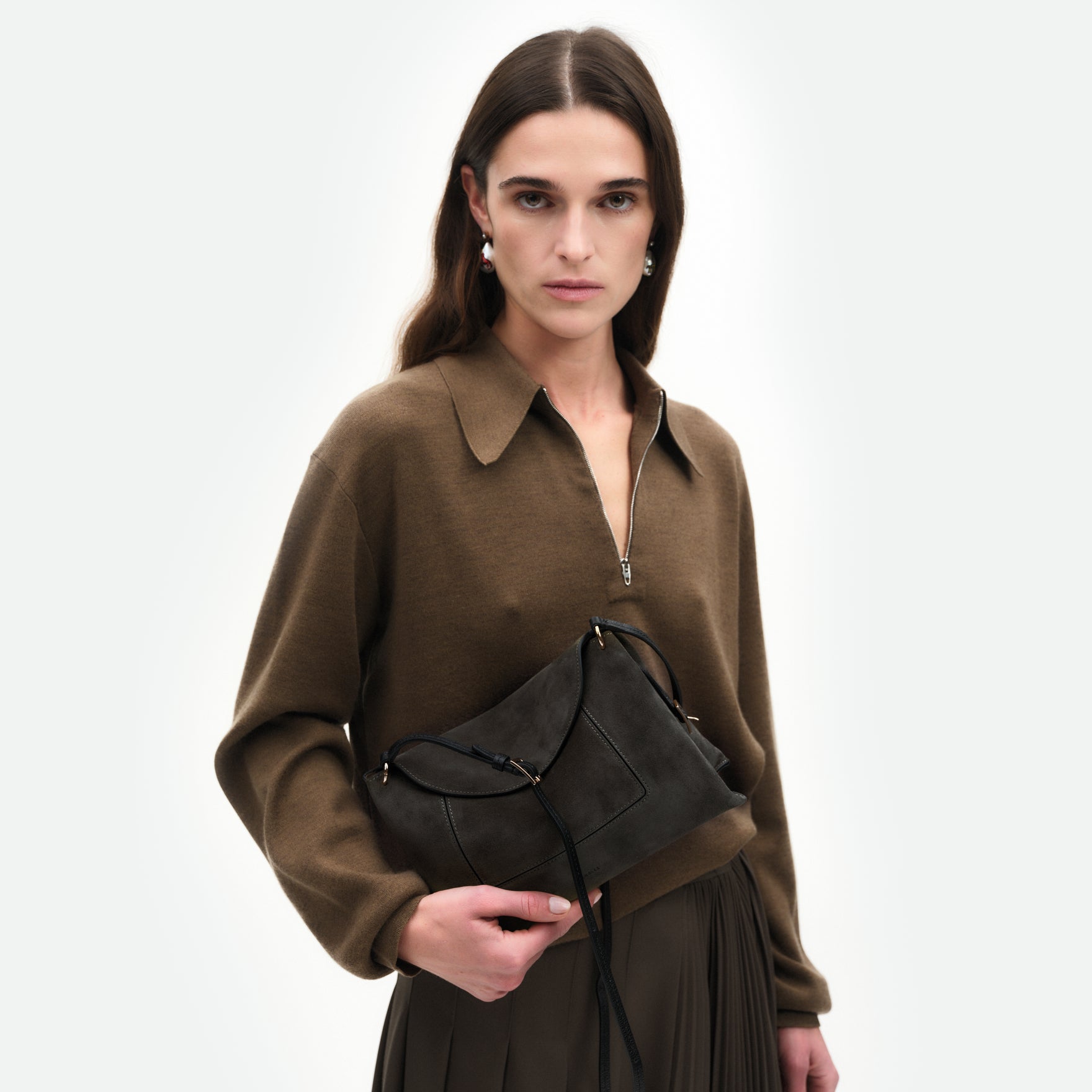Wandler Penelope Slouch Bag in the colour Space Suede, grey, made from smooth calf leather with golden hardware and adjustable slim strap, pictured being held in the hand by model, half body picture. 