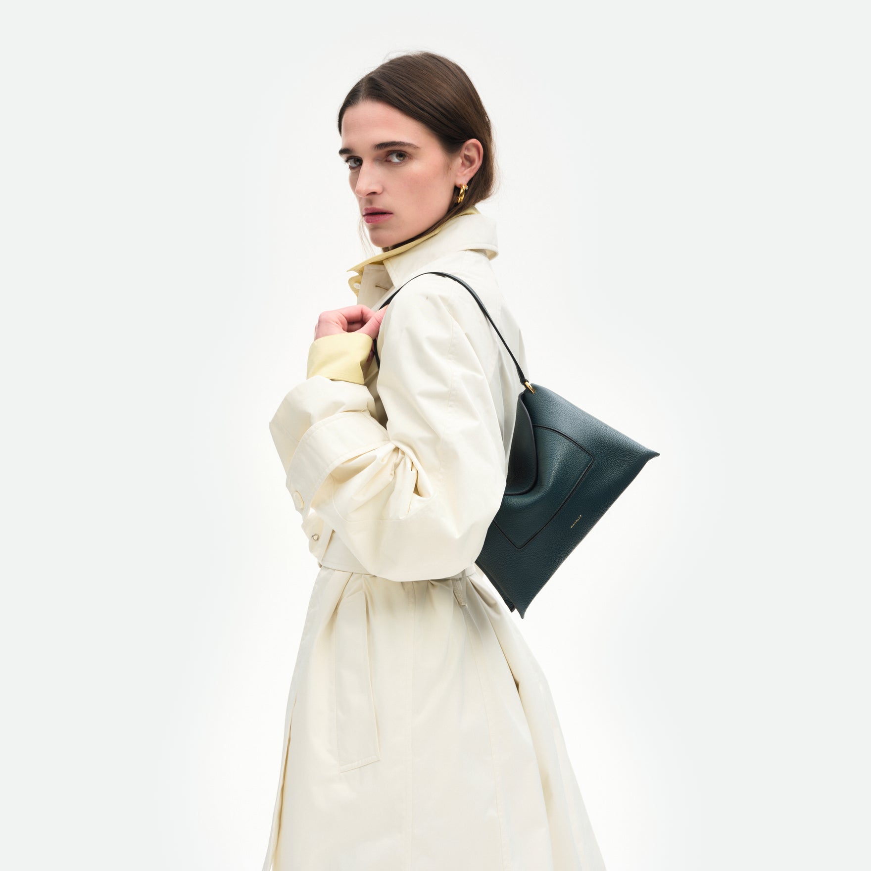 Wandler Penelope Slouch Bag in the color Pine Crust, made from calf leather with golden hardware and adjustable slim strap, pictured on model, worn on the shoulder, half body picture.