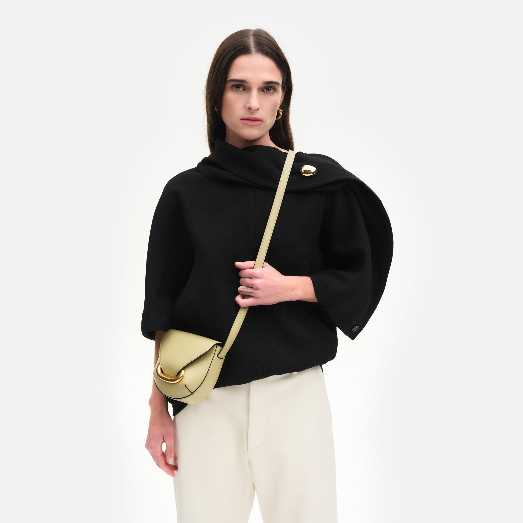 Wandler Veneto Crossbody Small in Peper, dark beige, made from Italian calf leather with golden clasp hardware and structured silhouette, pictured on model, worn in a crossbody style, half body picture. 