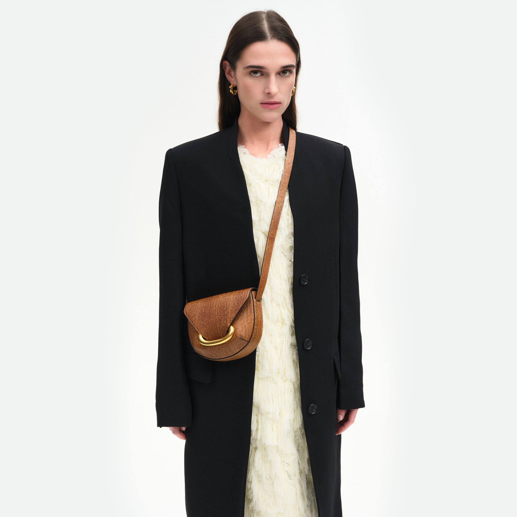 Wandler Veneto Crossbody Small in Tabacco Lizzard, warm brown with lizzard pattern, made from Italian calf leather with golden clasp hardware and structured silhouette, pictured on model, worn in crossbody style, half body picture. 