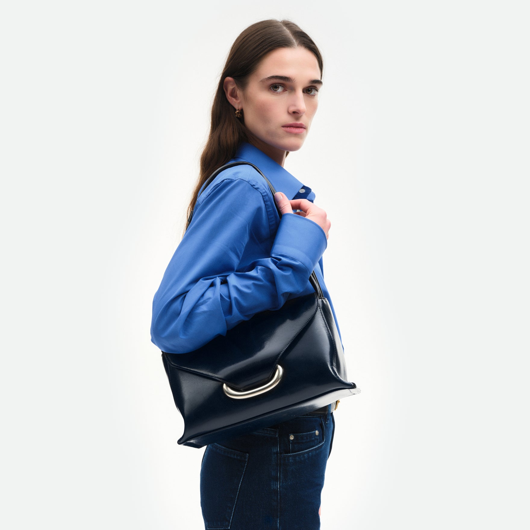 Wandler Veneto Shoulder Bag in the color Orion Glaze, deep dark blue, Italian calf leather with oversized silver clasp hardware and structured silhouette, pictured on model being worn on on the shoulder.