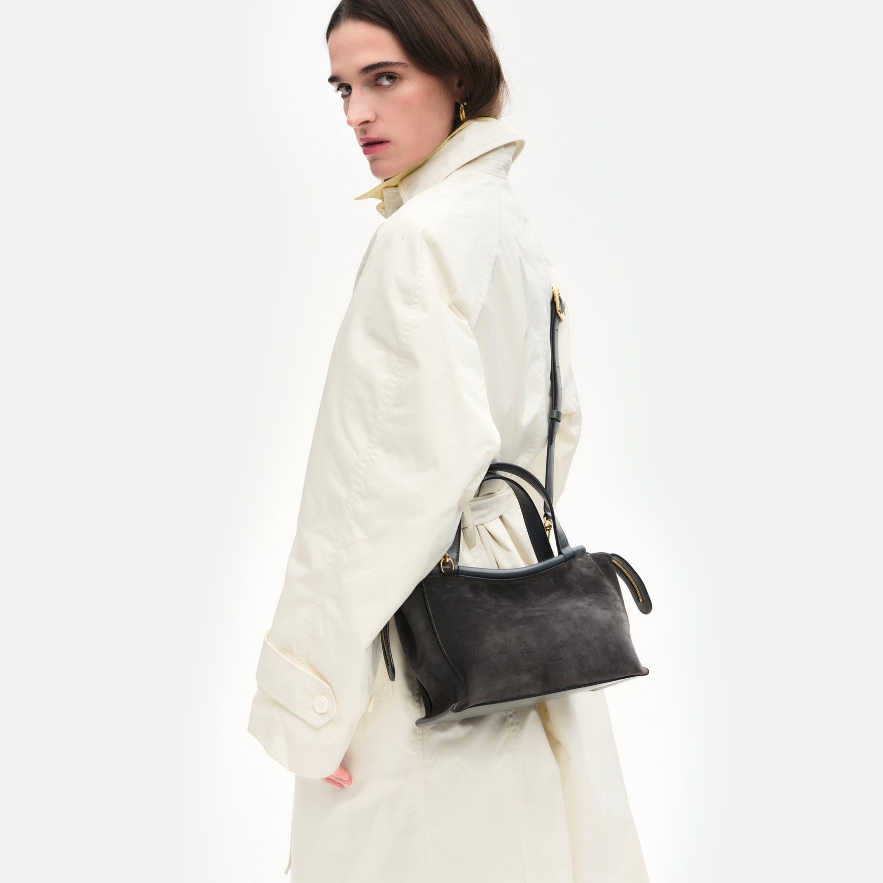 Wandler Ida Bag in the color Space Suede, made from Italian calf leather with golden hardware and sculptural top handle, pictured being worn on model in crossbody style. 