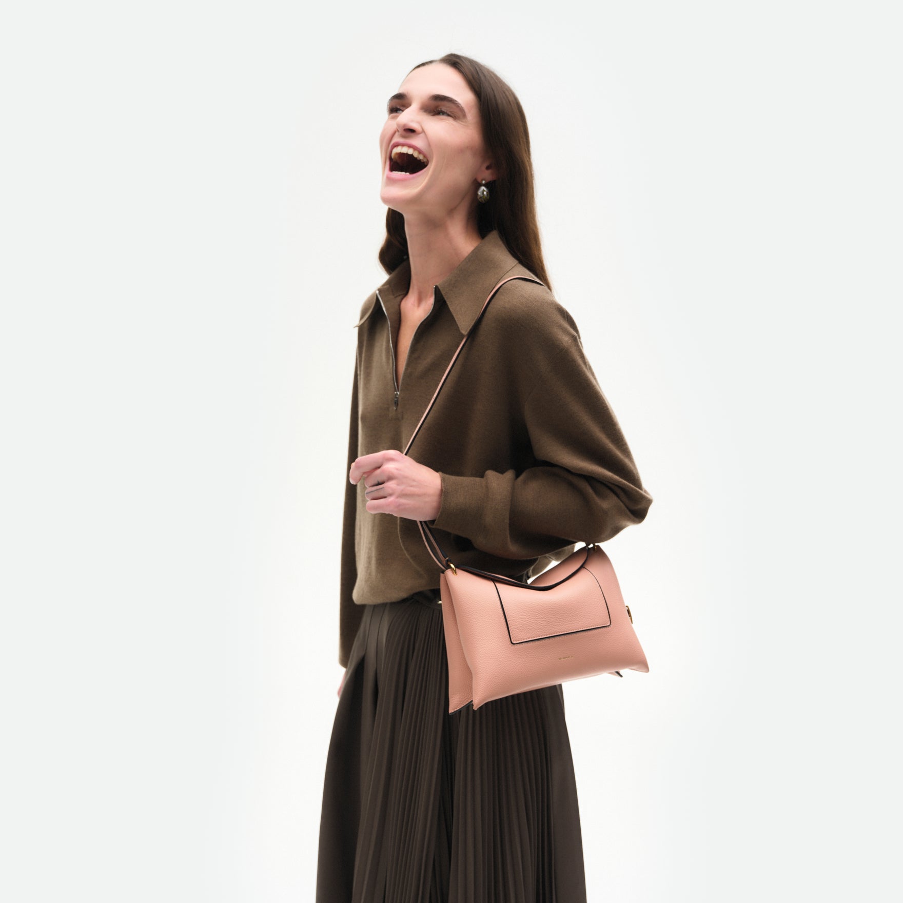 Wandler Penelope Slouch Bag in the color Apricot Crust, made from calf leather with golden hardware and adjustable slim strap, pictured on model being worn on the shoulder, half body picture. 