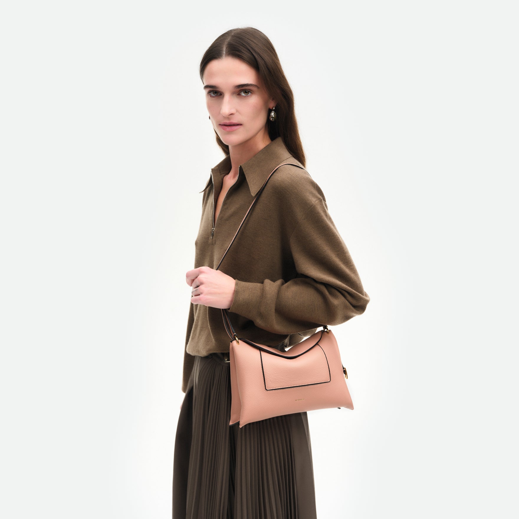 Wandler Penelope Slouch Bag in the color Apricot Crust, made from calf leather with golden hardware and adjustable slim strap, pictured on model, worn on the shoulder, half body picture.