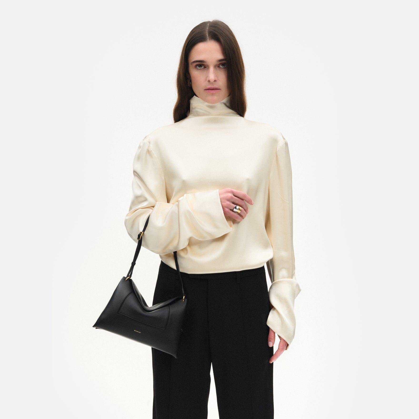 Wandler Penelope Slouch Bag in the color Black Crust, made from smooth calf leather with golden hardware and adjustable slim strap, pictured on model being worn on the forearm, half body picture. 