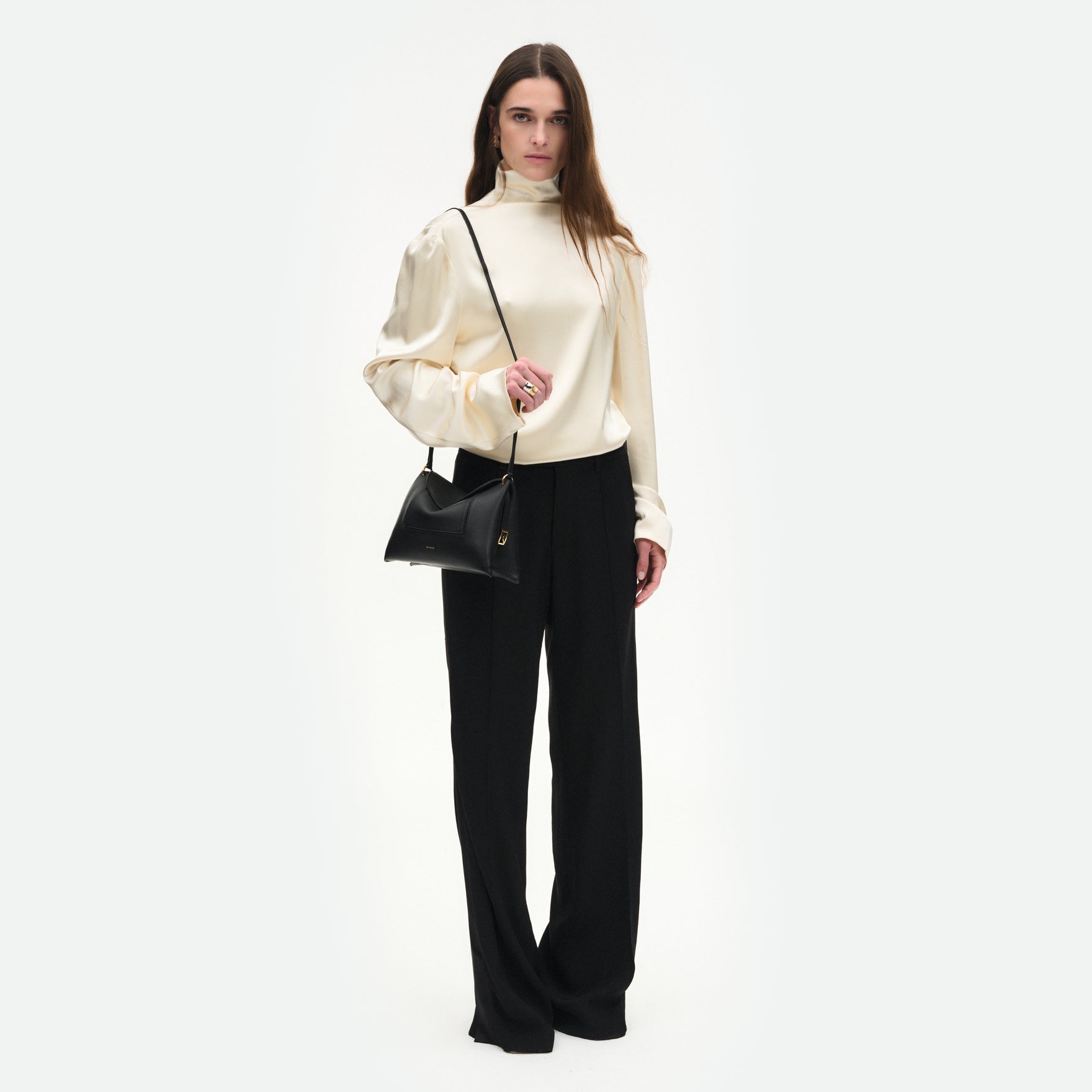 Wandler Penelope Slouch Bag in the color Black Crust, made from smooth calf leather with golden hardware and adjustable slim strap, pictured on model, worn on the shoulder, full body picture. 