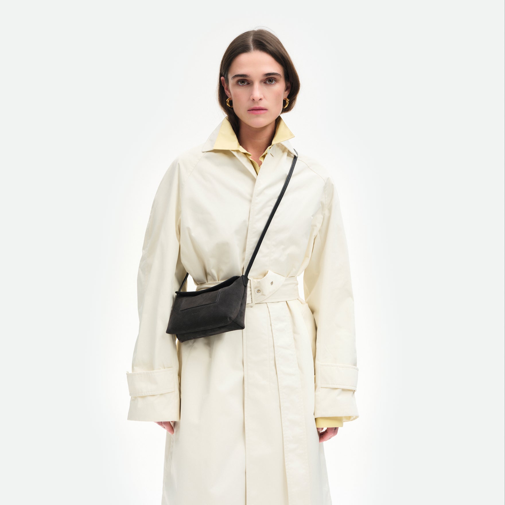 Wandler Penelope Slouch Mini in the color Space Suede, grey, made from Italian calf leather with golden hardware and slim adjustable strap, pictured on model, being worn in crossbody style, half body picture. 
