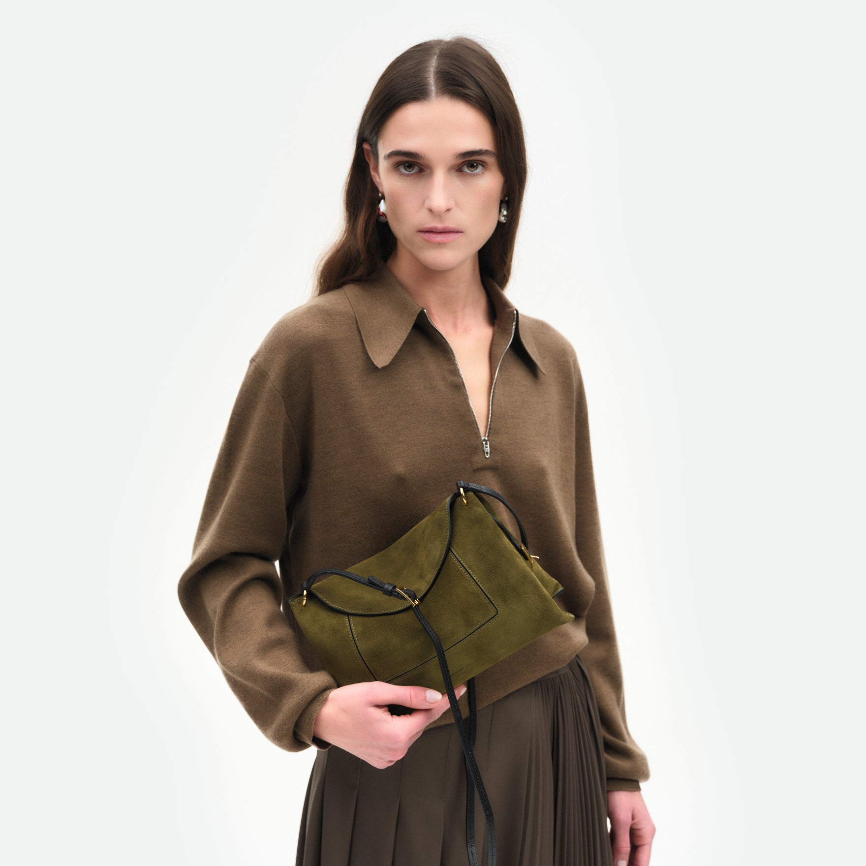 Wandler Penelope Slouch Bag in the color Orion Crust deep dark blue, made from calf leather with golden hardware and adjustable slim strap, pictured being held in the hand by model, half body picture. 