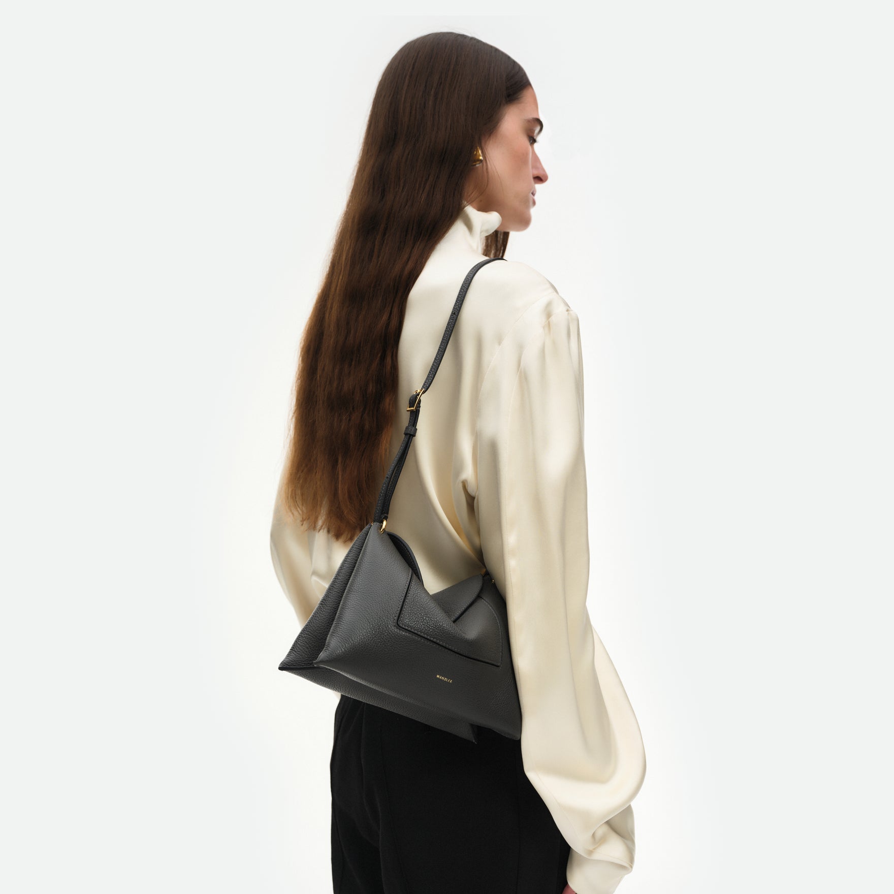 Wandler Penelope Slouch Bag in the colour Space Crust, grey, made from smooth calf leather with golden hardware and adjustable slim strap, pictured on model, worn on the shoulder. 