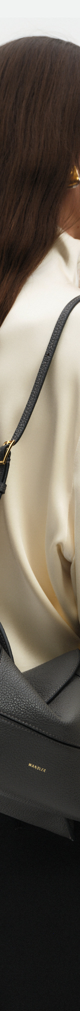 Wandler Penelope Slouch Bag in the colour Space Crust, grey, made from smooth calf leather with golden hardware and adjustable slim strap, pictured on model, worn on the shoulder. 