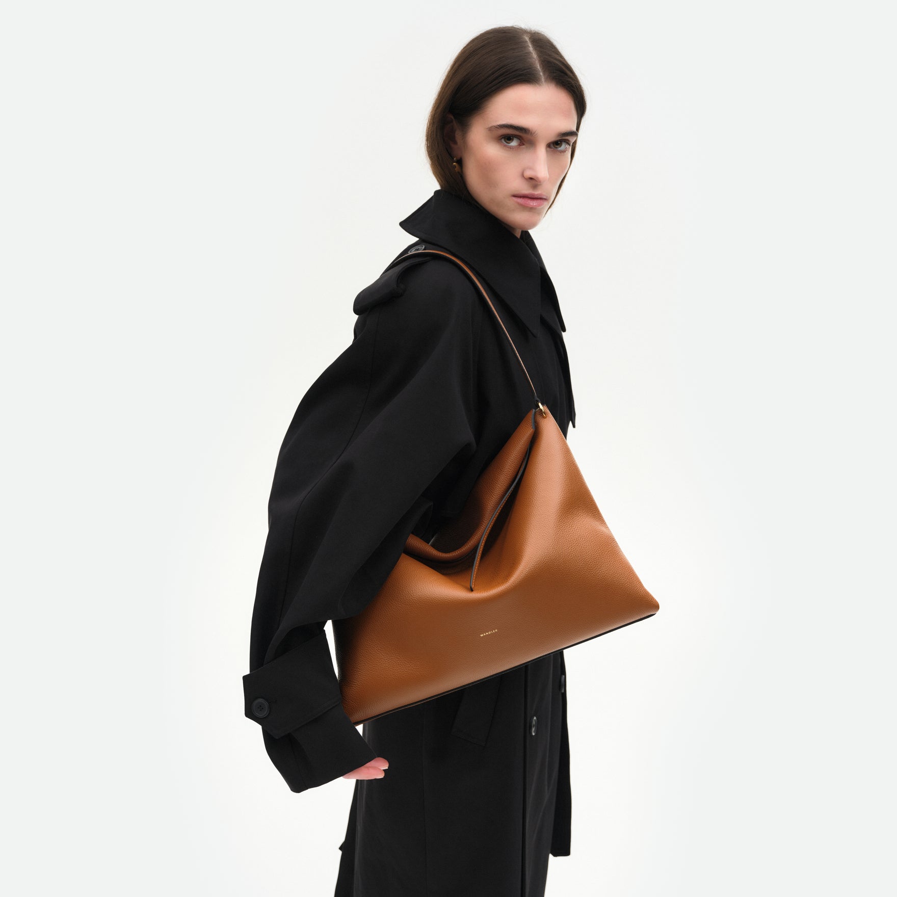 Wandler Penelope Tote in the color Tan Crust, made from Italian calf leather with golden hardware and soft structured silhouette, pictured being worn on the shoulder by model.