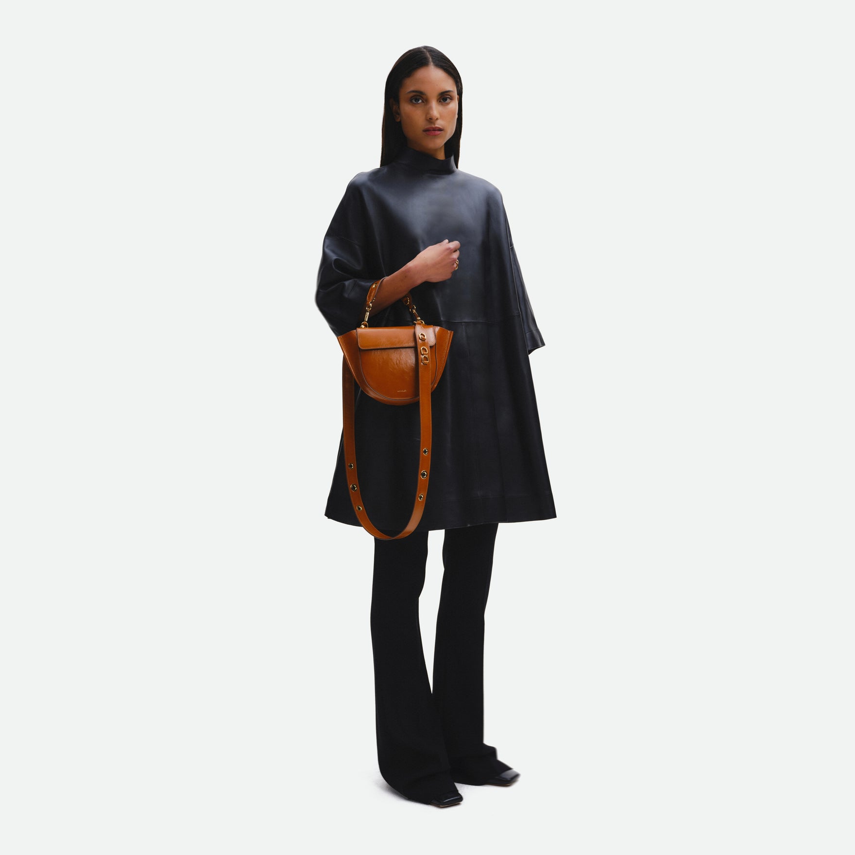 Wandler Hortensia Bag Mini in the color Cognac Eyelets, caramel brown, Italian calf leather with golden hardware, rounded silhouette and top handle, pictured being held on the forearm by model, full body picture.