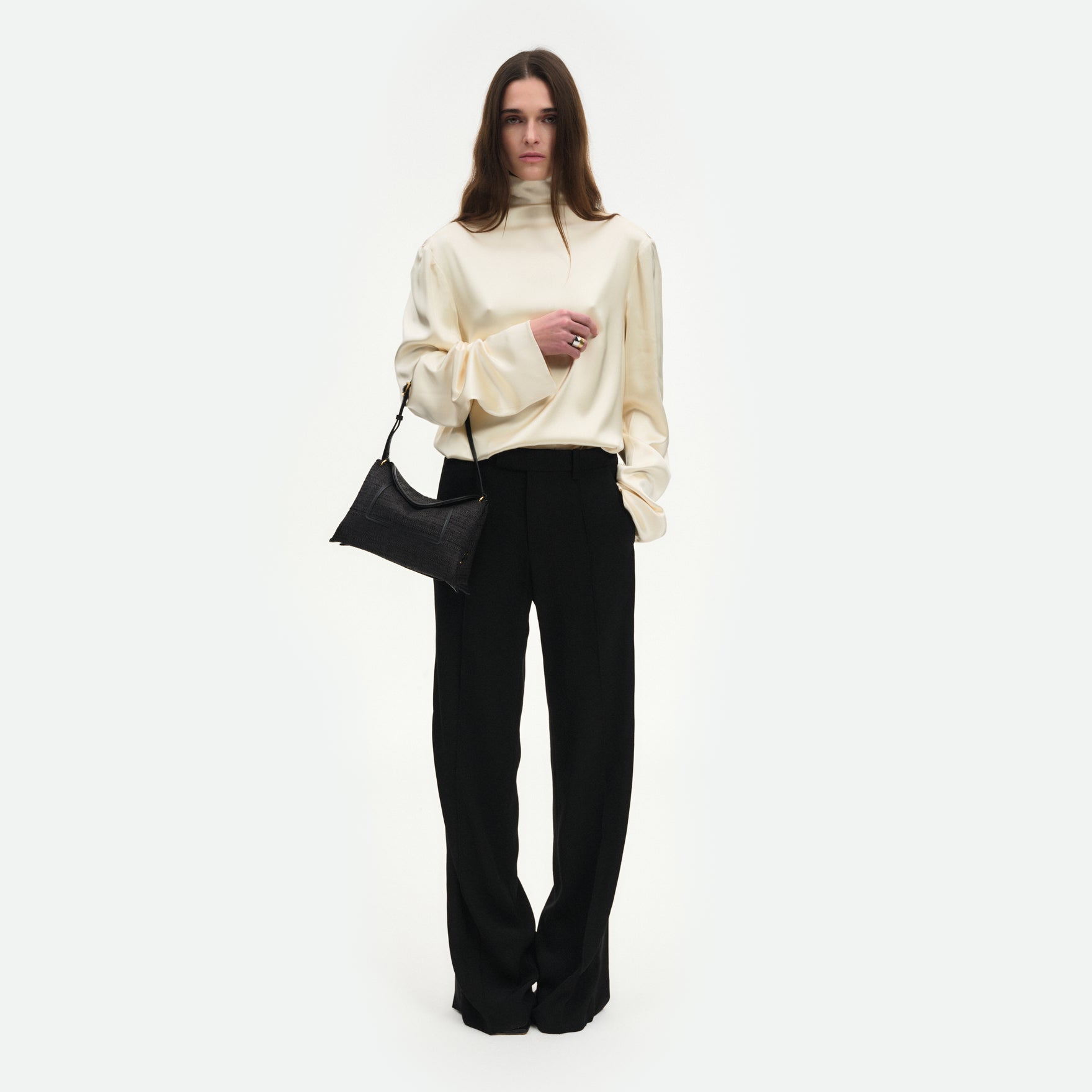 Wandler Penelope Slouch Bag in the color Black Raffia, made from raffia and smooth calf leather with golden hardware and adjustable slim strap, pictured being worn on the forearm by the model, full body picture.