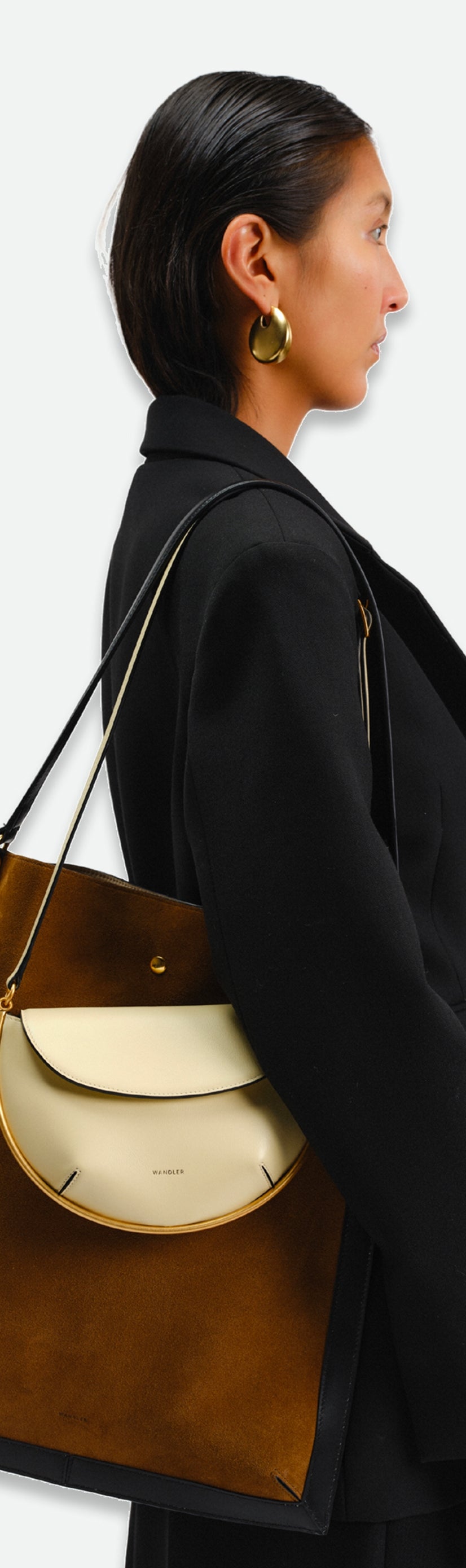 Wandler Penny Tote in the color Tabacco Suede, made from Italian calf leather with hand-painted black edges and golden hardware, being worn on the shoulder by model together with other bag.