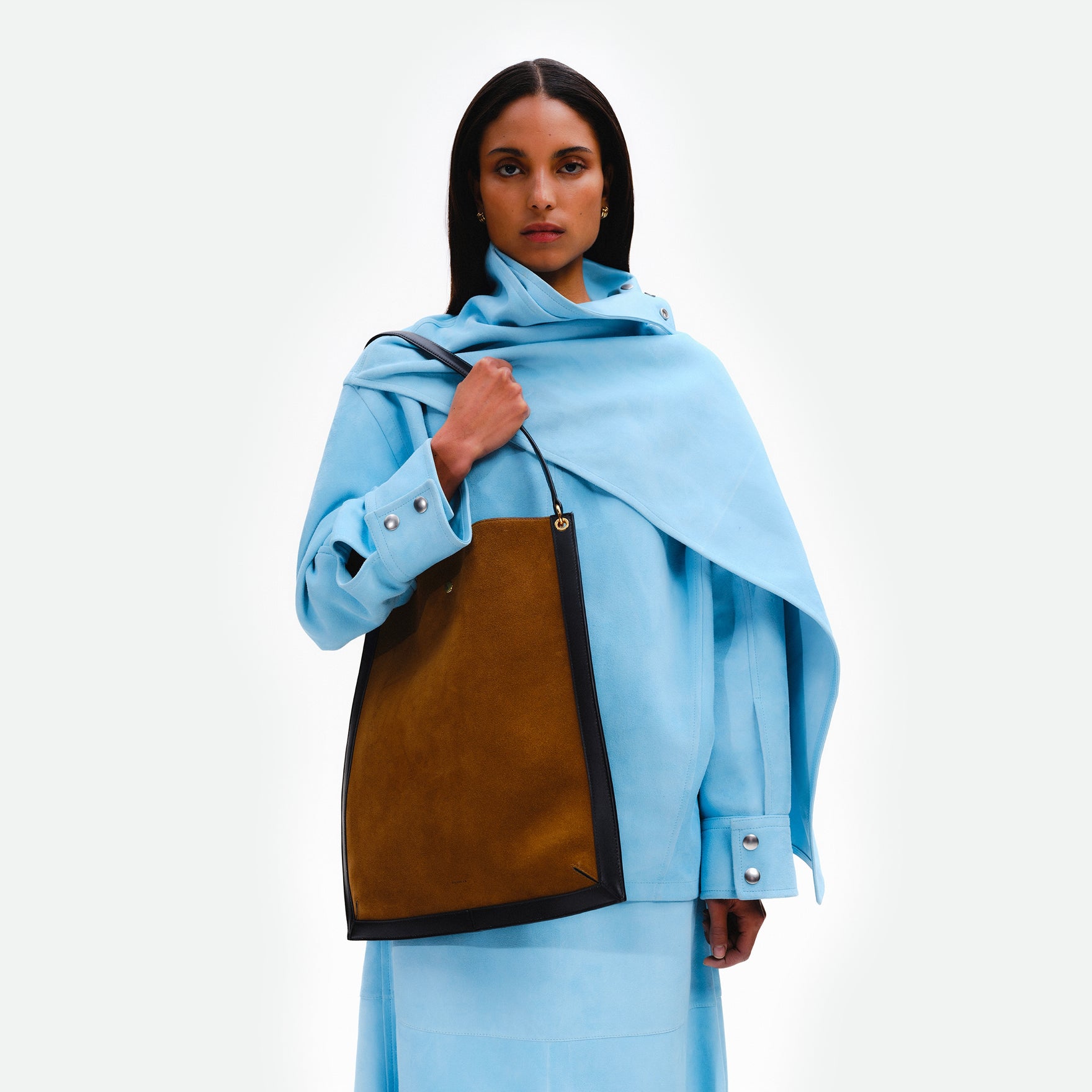 Wandler Penny Tote in the color Tabacco Suede, made from Italian calf leather with hand-painted black edges and golden hardware, pictured being worn on the shoulder by model.