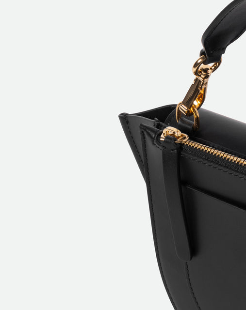 Wandler Hortensia Bag Mini in the color black, Italian calf leather with golden hardware, rounded silhouette and top handle, detail shot featuring a close up of the zipper and handle. 