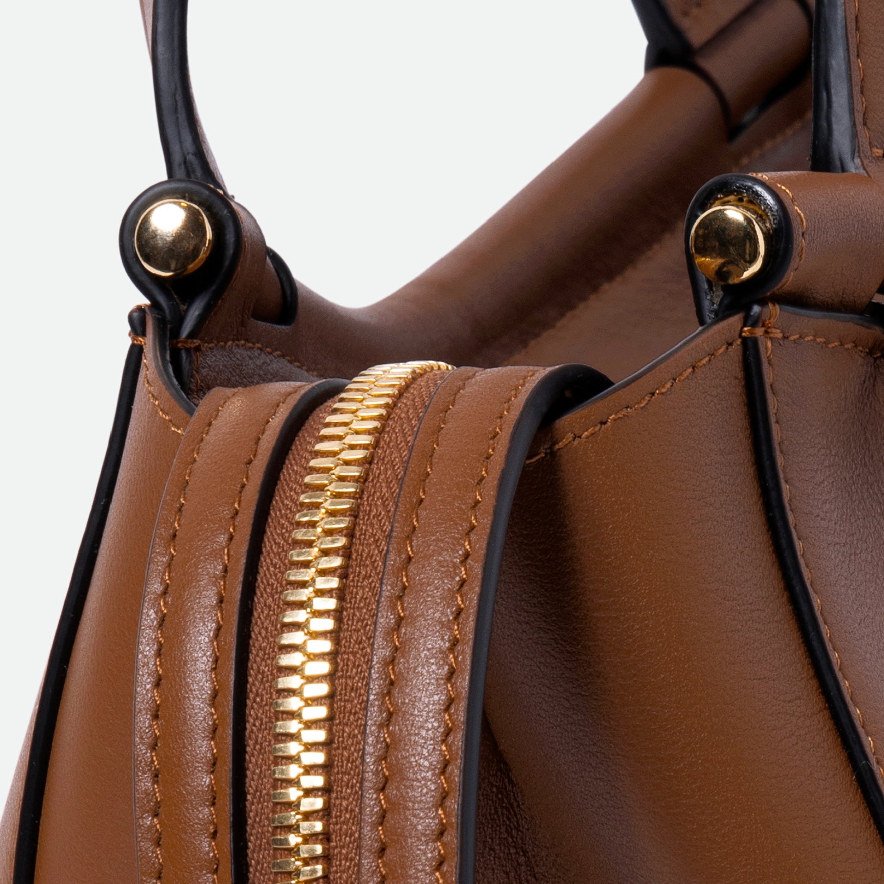 Wandler Ida Bag in the color Saddle, warm brown, made from Italian calf leather with golden hardware and sculptural top handle, close up detailing the zipper. 