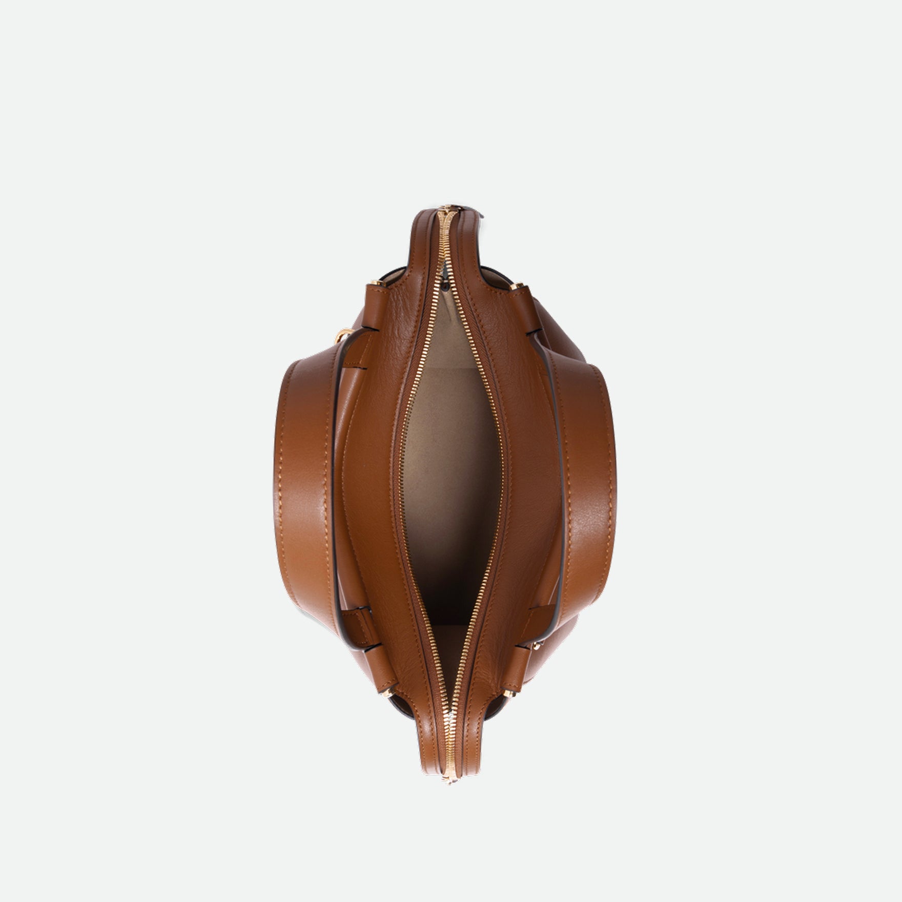 Wandler Ida Bag in the color Saddle, warm brown, made from Italian calf leather with golden hardware and sculptural top handle, bag pictured from above with the zipper open, giving a glimpse into the inside of the bag. 