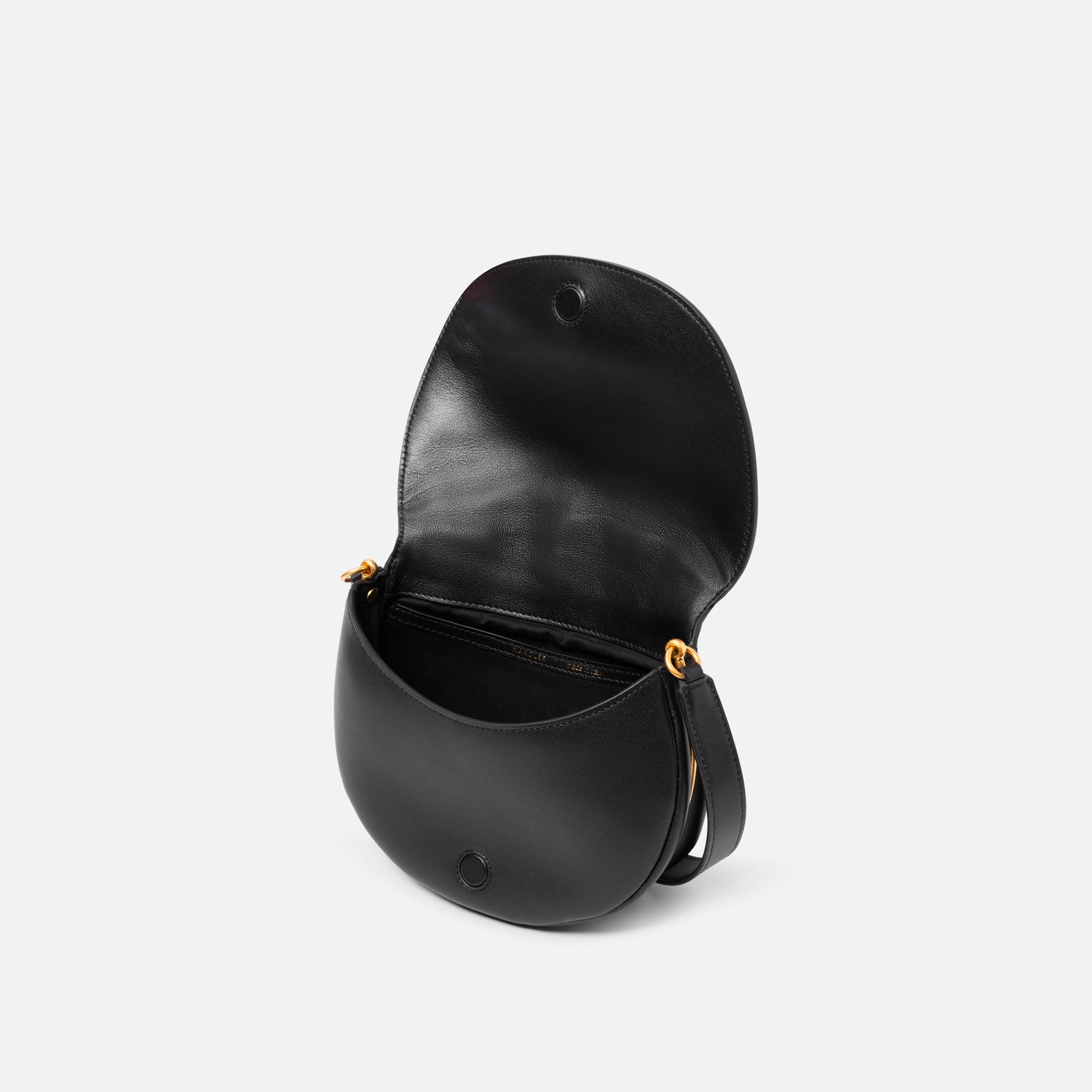 Wandler Kate Bag in the color Black, made from Italian calf leather with golden hardware and adjustable shoulder strap, pictured from above with the flap open, giving a glimpse into the inside of the bag. 