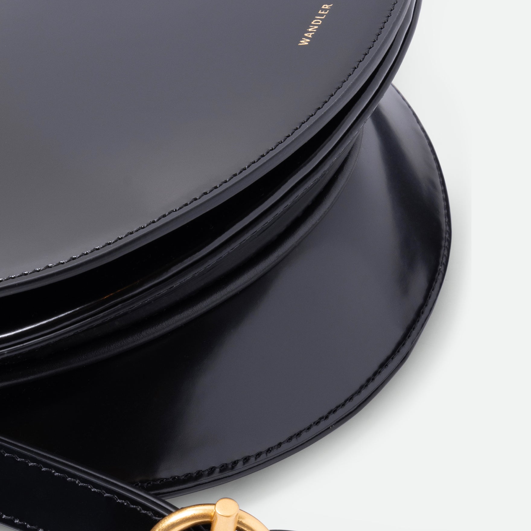 Wandler Kate Saddle Bag in the color Jazz Olive, deep dark green, calf leather with golden hardware and adjustable shoulder strap, close up detailing the leather.