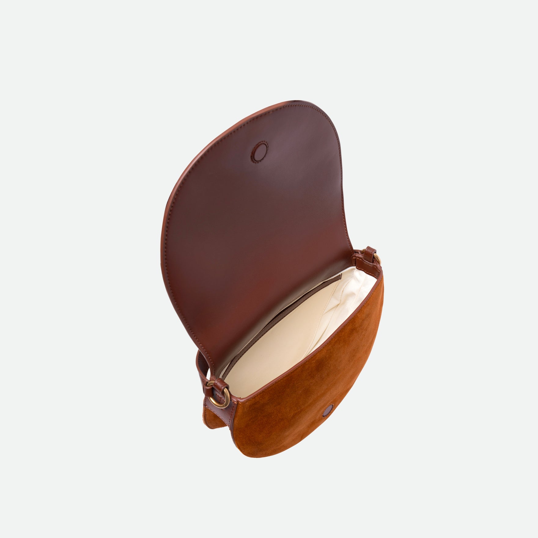 Wandler Kate Saddle Bag in the color Tan Suede, warm brown, calf leather with golden hardware and adjustable shoulder strap, pictured from above with the flap open, showing a glimpse of the inside of the bag. 
