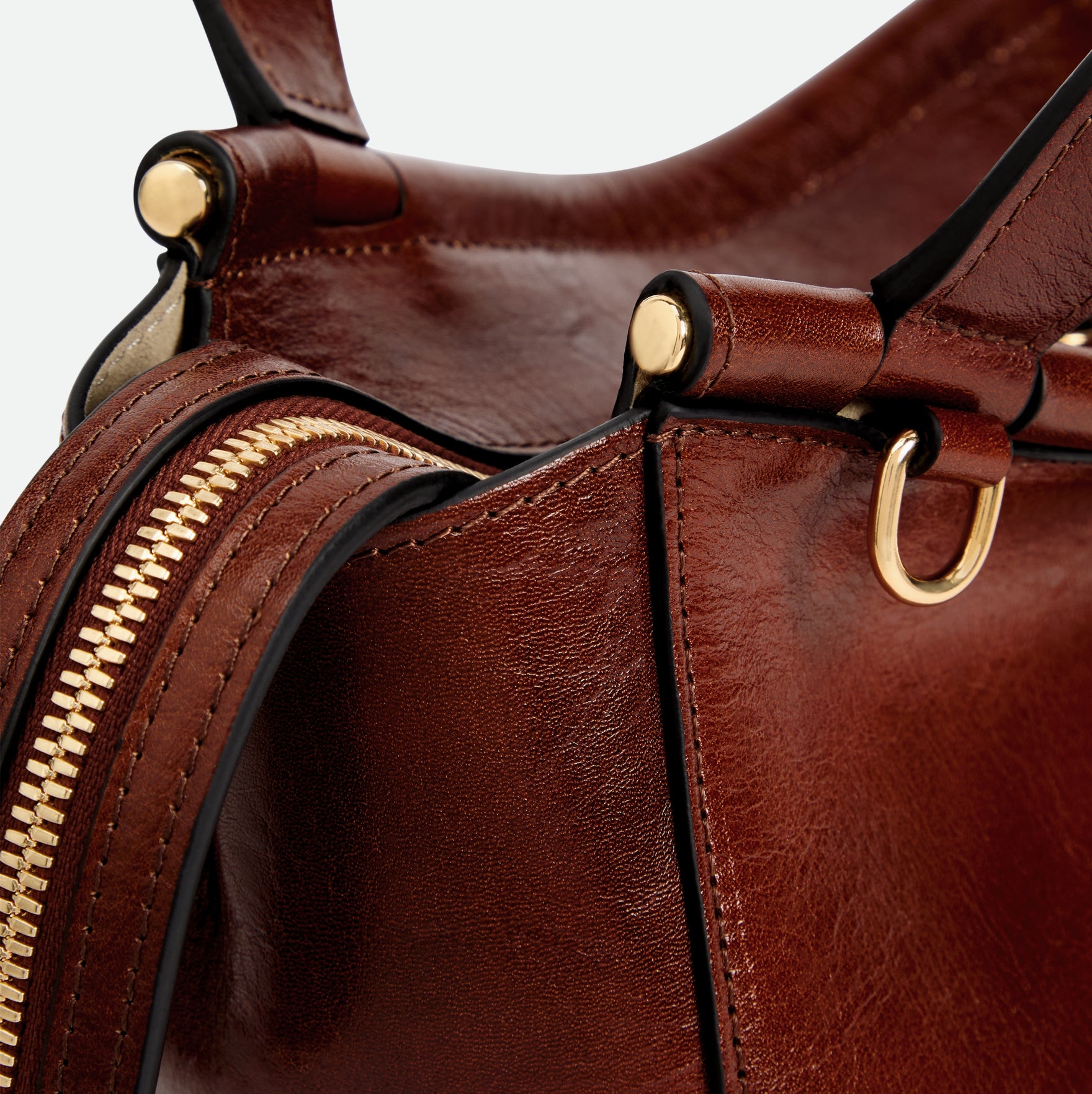 Wandler Ida Bag in the color Palissander Glaze, deep dark brown with red undertones, made from Italian calf leather with golden hardware and sculptural top handle, close up detailing the side of the bag as well as the leather and zipper. 