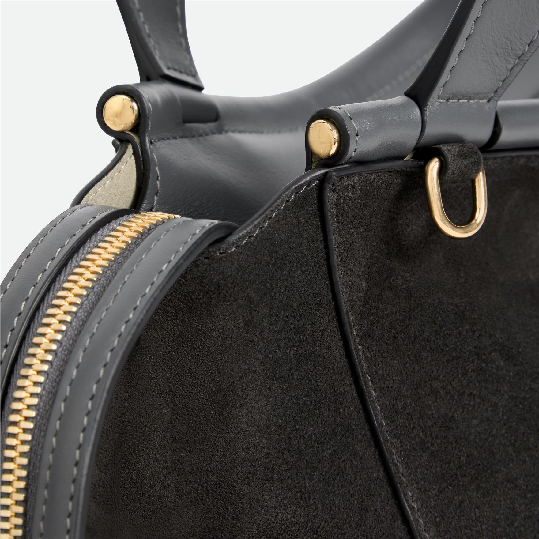 Wandler Ida Bag in the color Space Suede, made from Italian calf leather with golden hardware and sculptural top handle, close up detailing the side of the bag as well as the leather and zipper. 