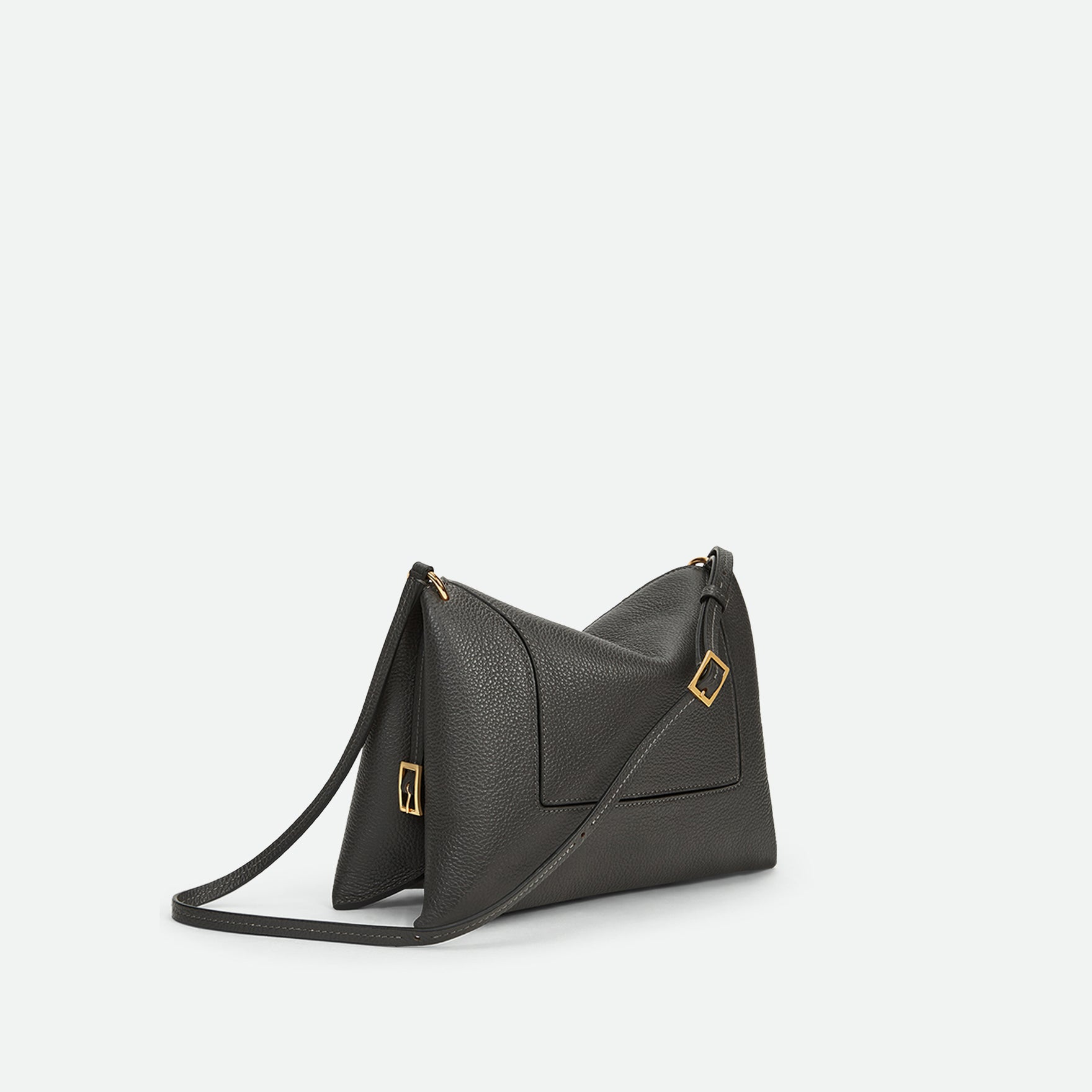 Wandler Penelope Slouch Bag in the colour Space Crust, grey, made from smooth calf leather with golden hardware and adjustable slim strap, side view from three quarters angle. 