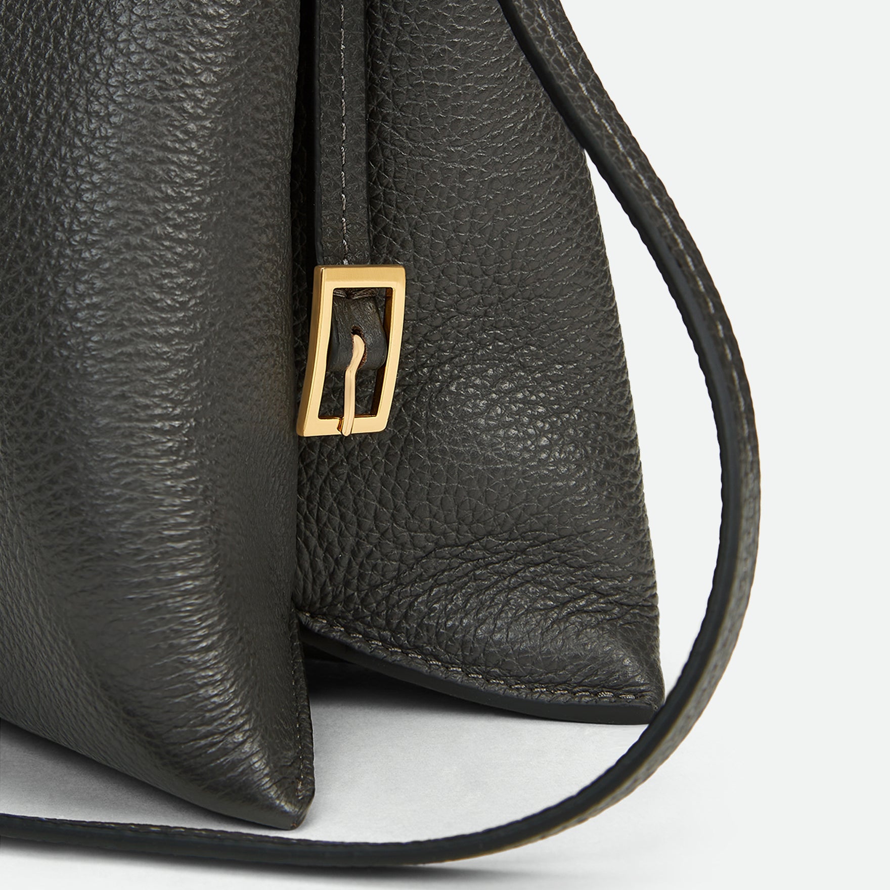 Wandler Penelope Slouch Bag in the colour Space Crust, grey, made from smooth calf leather with golden hardware and adjustable slim strap, close up detailing the clasp and side of the bag.