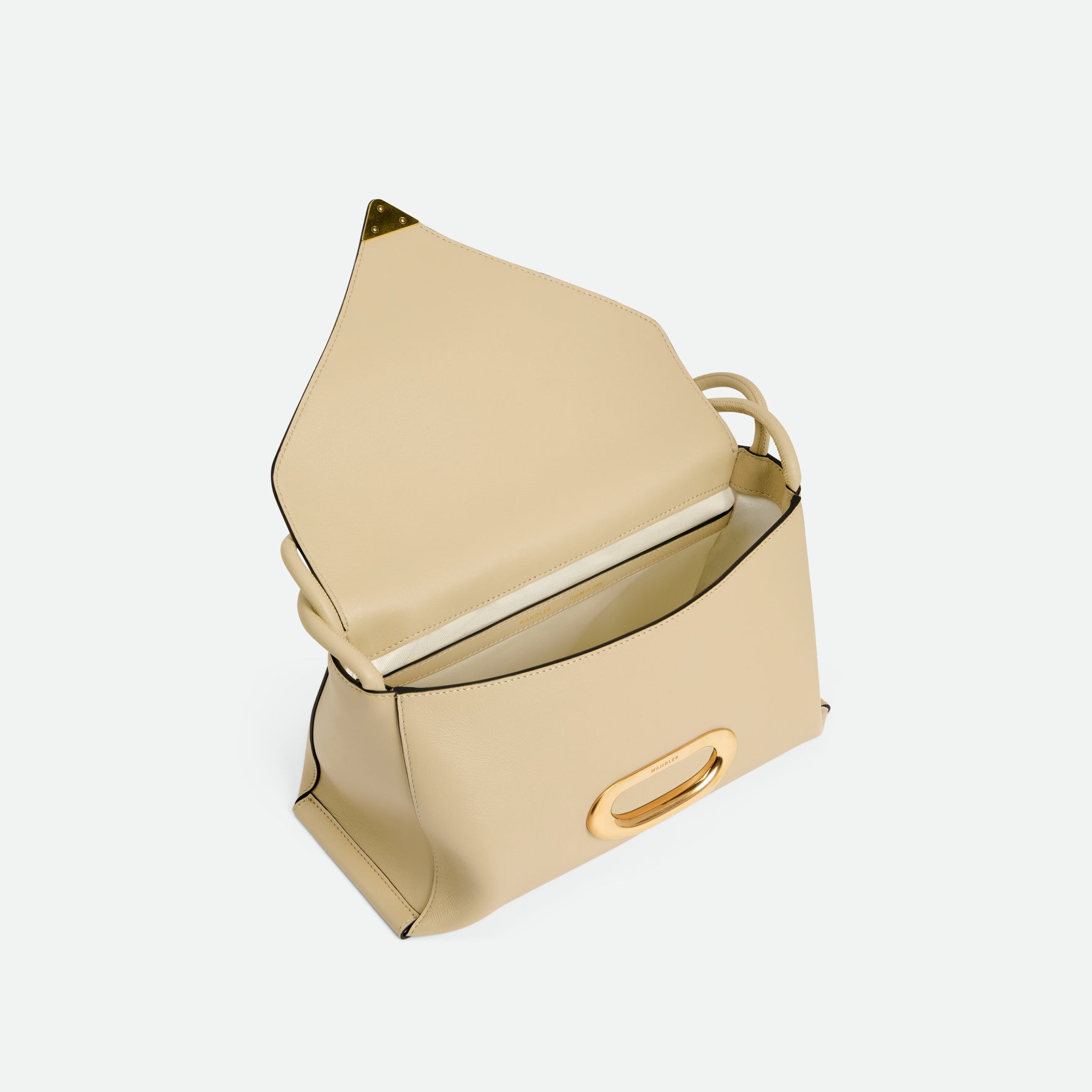 Wandler Veneto Shoulder Bag in the color Linen, beige, Italian calf leather with oversized golden clasp hardware and structured silhouette. The bag is pictured from the front with the flap open, giving a slight view of the inside of the bag.
