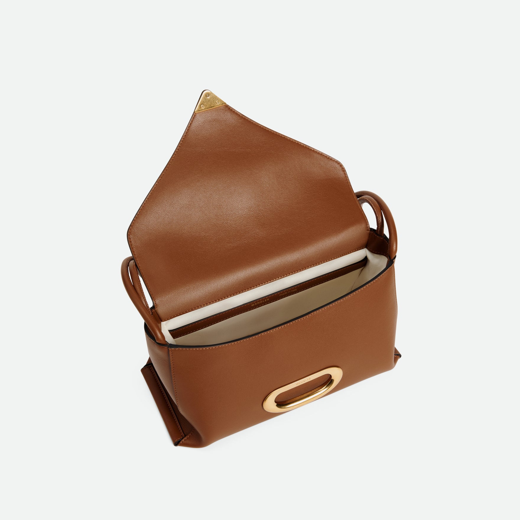 Wandler Veneto Shoulder Bag in the color Saddle, warm brown, Italian calf leather with oversized golden clasp hardware and structured silhouette. The bag is pictured from above with the flap open, giving a slight view of the inside of the bag.
