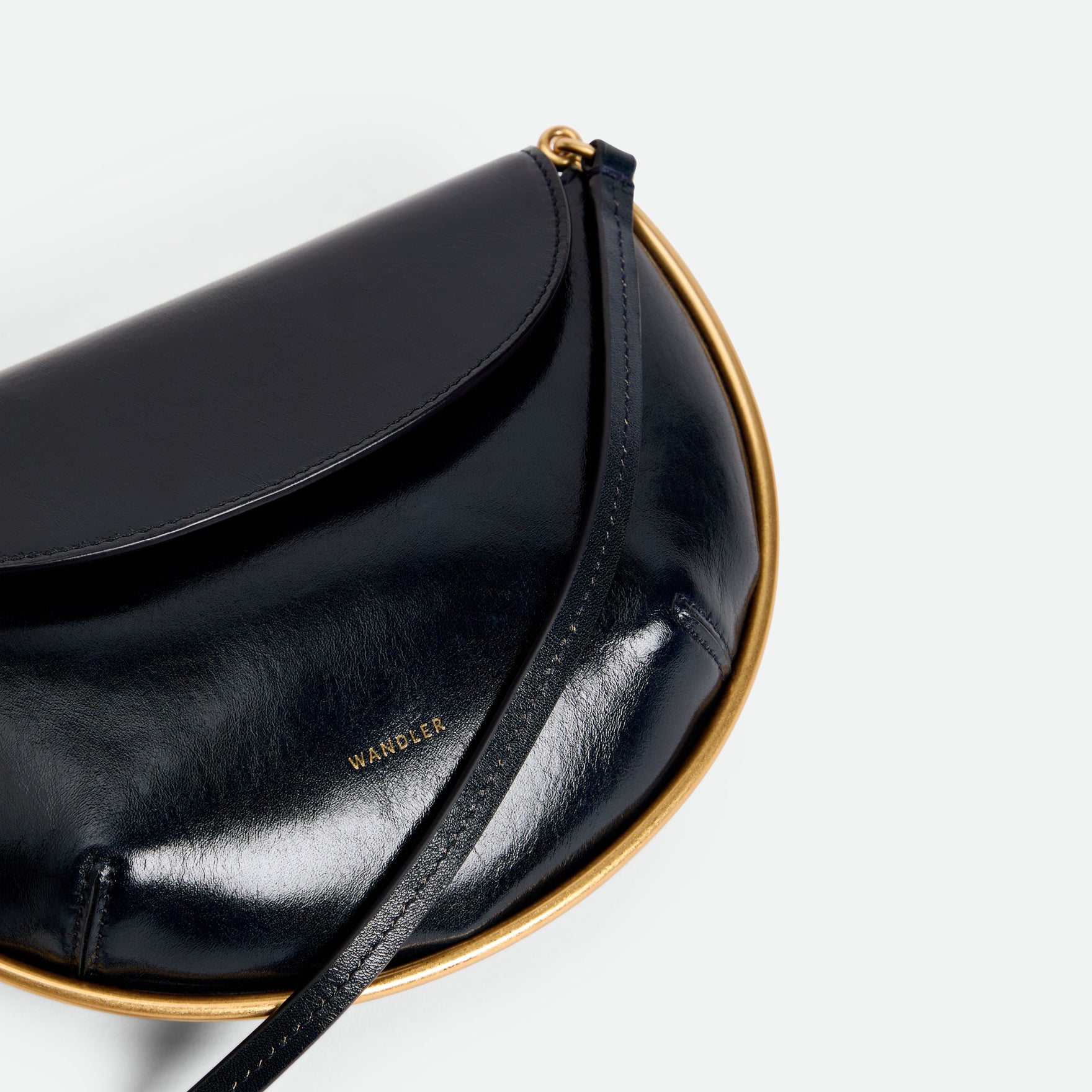 Wandler Kate Mini Crossbody in the color Orion Glaze, deep dark blue, made from Italian calf leather with golden hardware and adjustable strap, close up detailing the leather and the logo. 