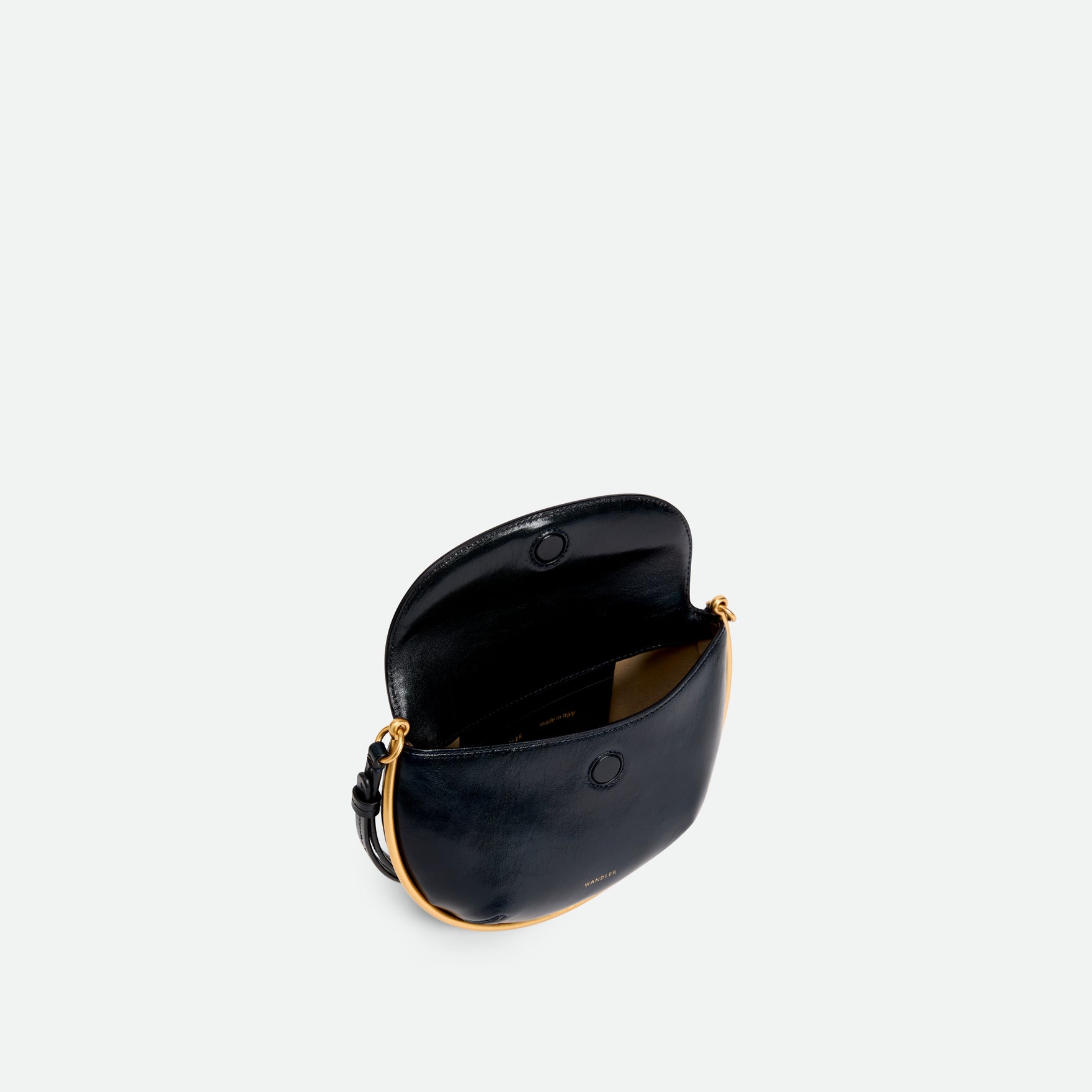 Wandler Kate Mini Crossbody in the color Orion Glaze, deep dark blue, made from Italian calf leather with golden hardware and adjustable strap, bag being pictured open and from above, showing a glimpse of the inside of the bag. 
