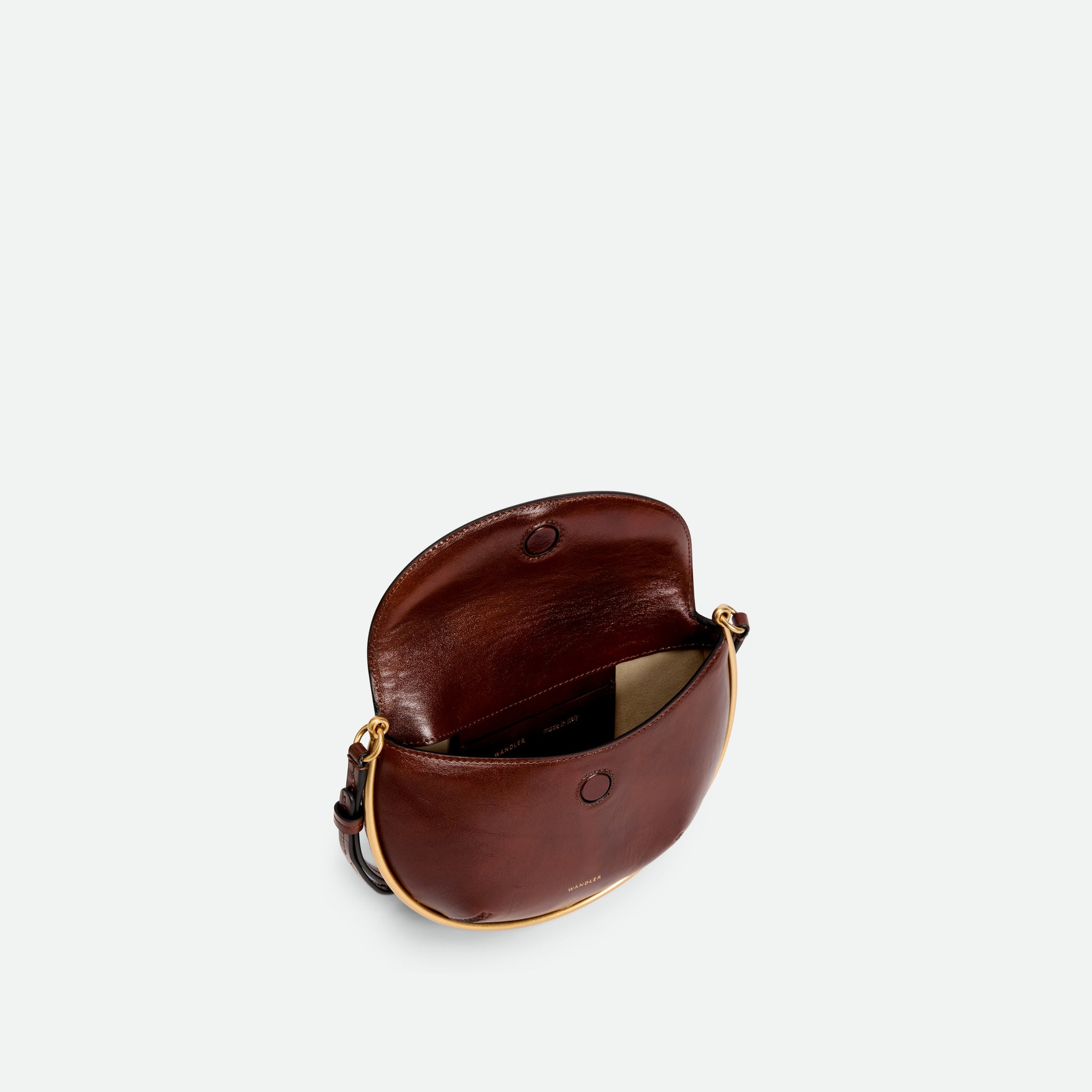 Wandler Kate Mini Crossbody in the color Palissander Glaze, Deep dark brown with red undertones, made from Italian calf leather with golden hardware and adjustable strap, pictured from above with the flap open, giving a glimpse of the inside of the bag. 