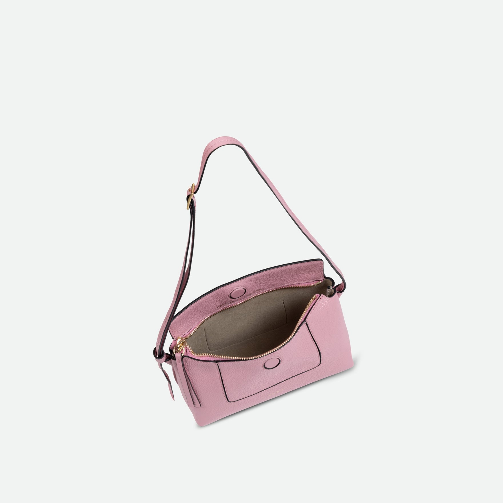 Wandler Penelope Slouch Mini in Rose Crust, pink, Italian calf leather with golden hardware and slim adjustable strap, pictured on model worn on the shoulder. The bag is pictured from above with the flap and zipper open, giving a slight view of the inside of the bag.
