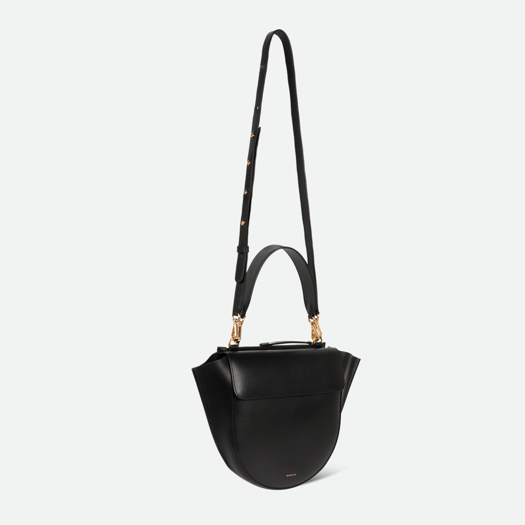 Wandler Hortensia Bag Medium in the color Black, made from Italian calf leather with golden hardware, rounded silhouette and top handle, pictured from three quarters angle with the straps suspended into the air. 