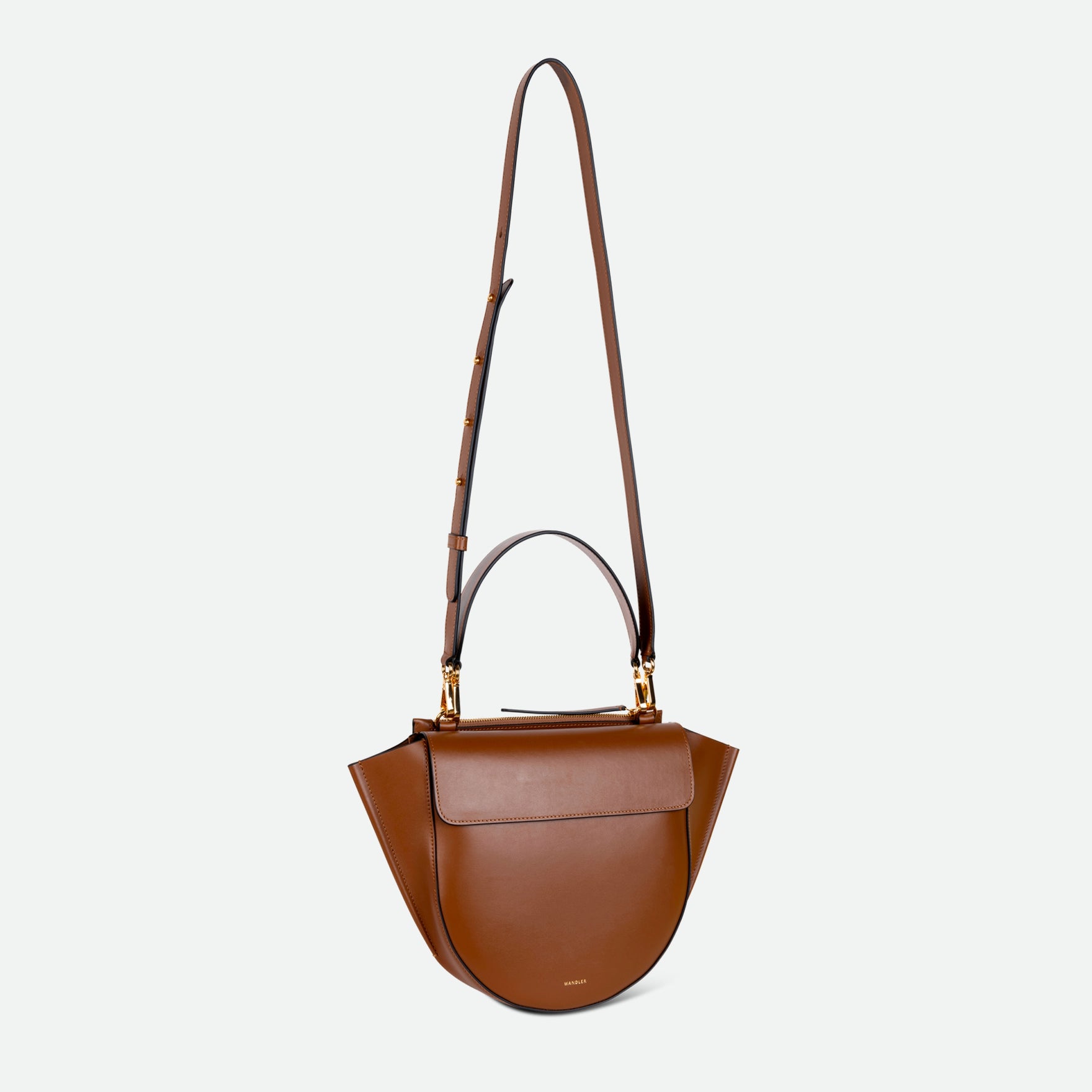 Wandler Hortensia Bag Medium in the color Saddle, warm brown, made from Italian calf leather with golden hardware, rounded silhouette and top handle, pictured with the straps suspended into the air. 