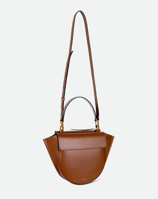 Wandler Hortensia Bag Medium in the color Saddle, warm brown, made from Italian calf leather with golden hardware, rounded silhouette and top handle, pictured with the straps suspended into the air. 