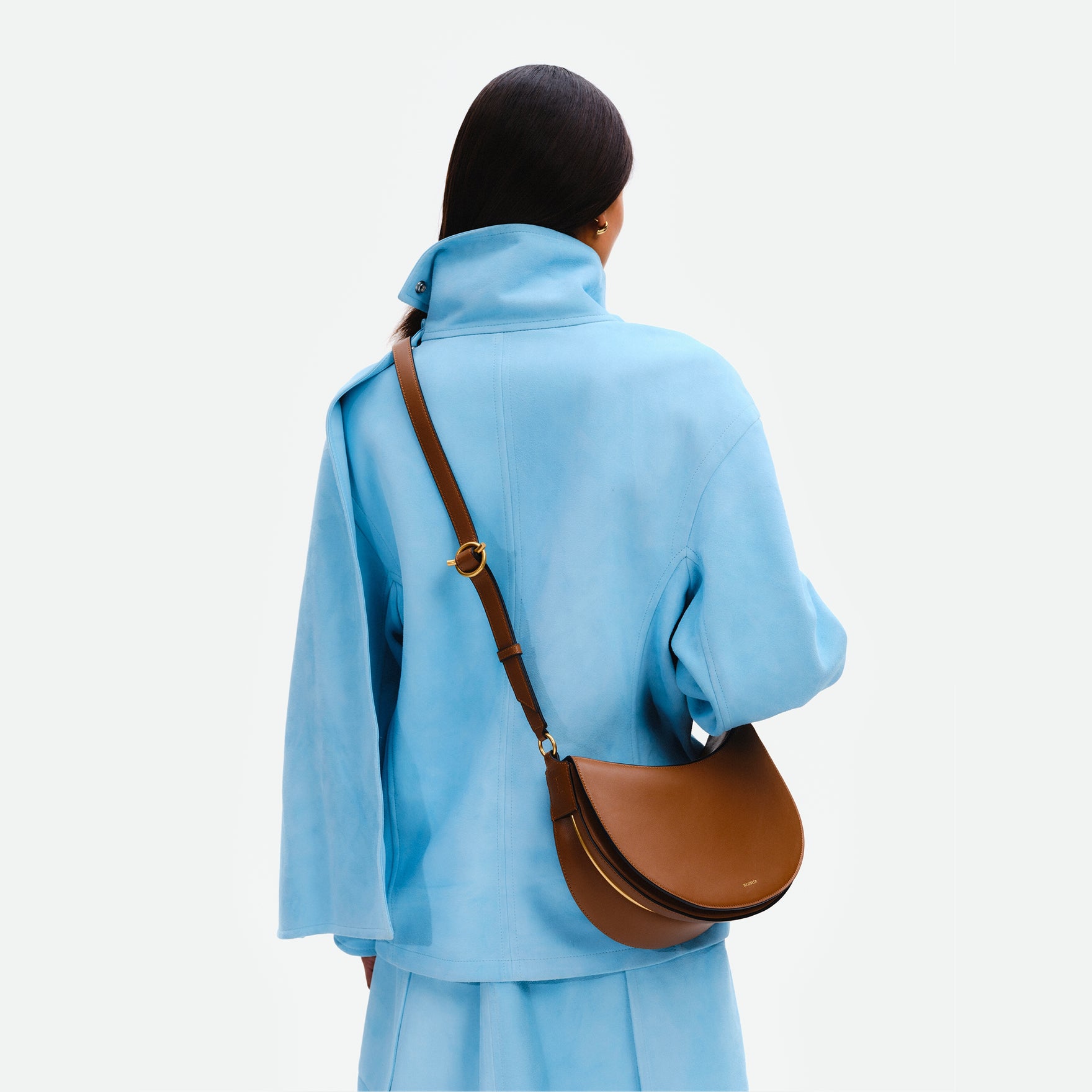 Wandler Kate Bag Big in the color Saddle, made from Italian calf leather with golden hardware and adjustable shoulder strap, pictured being worn by model on the shoulder, backside view.