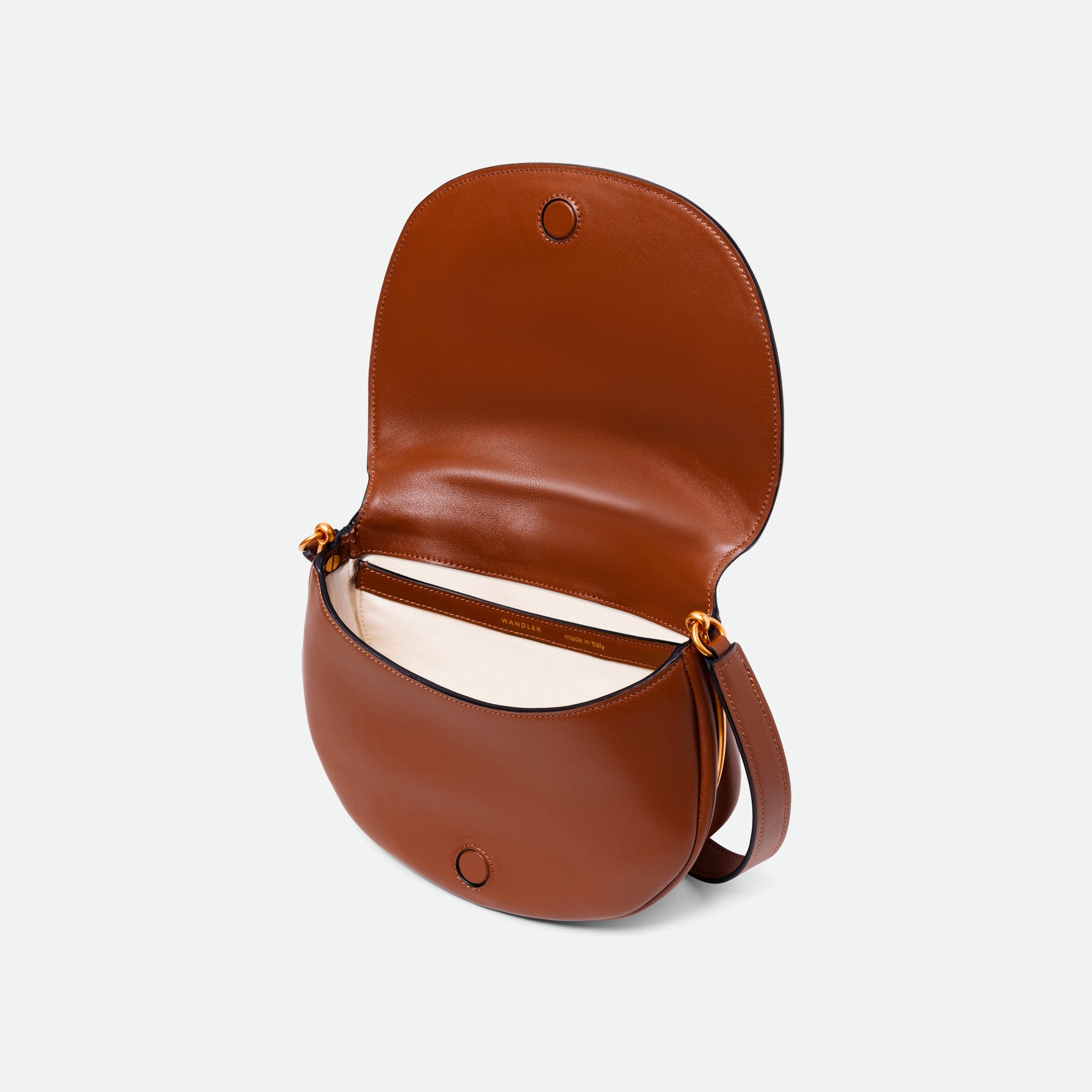 Wandler Kate Bag Big in the color Saddle, made from Italian calf leather with golden hardware and adjustable shoulder strap, pictured with the flap open, giving a glimpse into the inside of the bag.